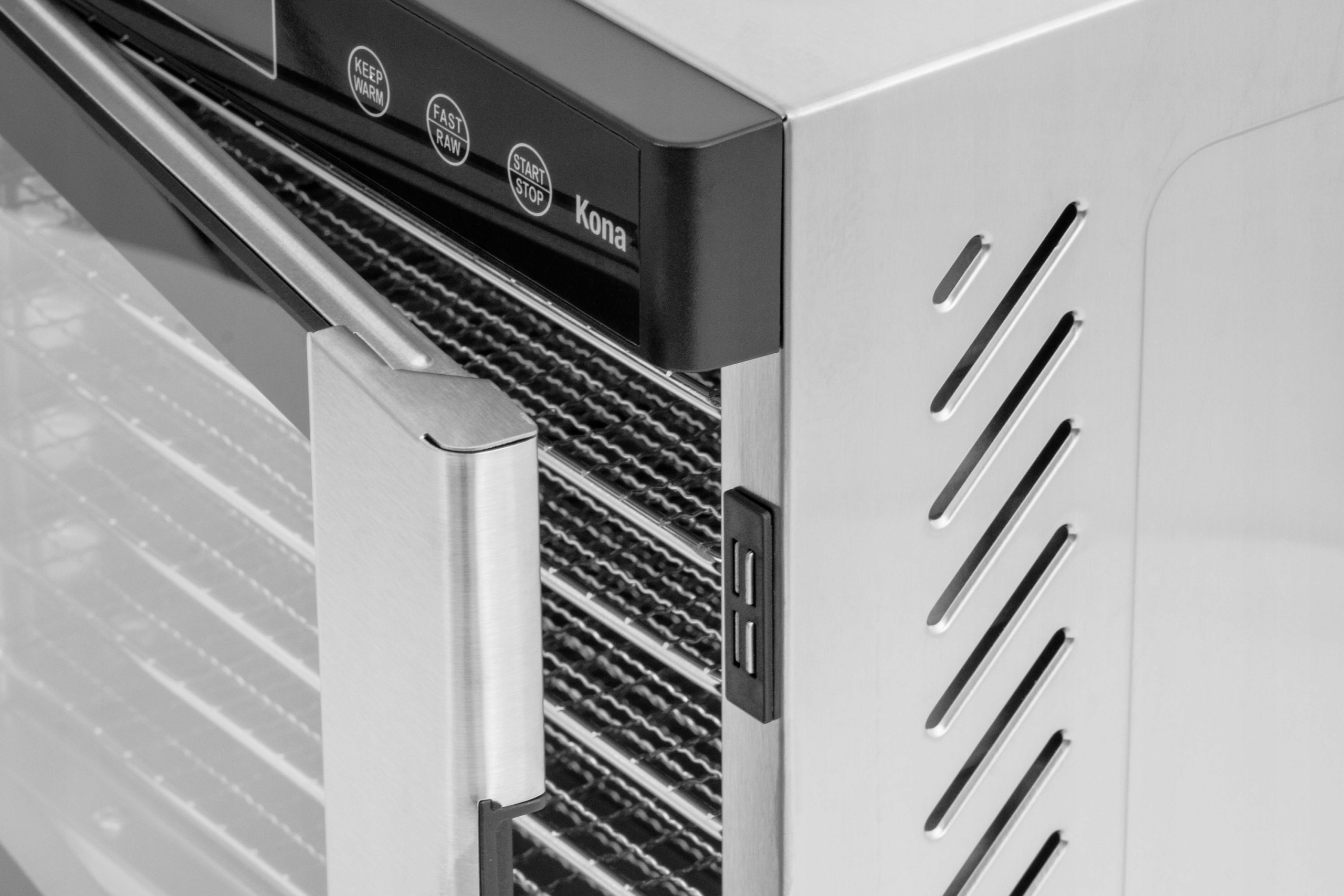 Zbliżenie rogu suszarki, pokazujące drzwi, metalowe półki i panel sterowania.