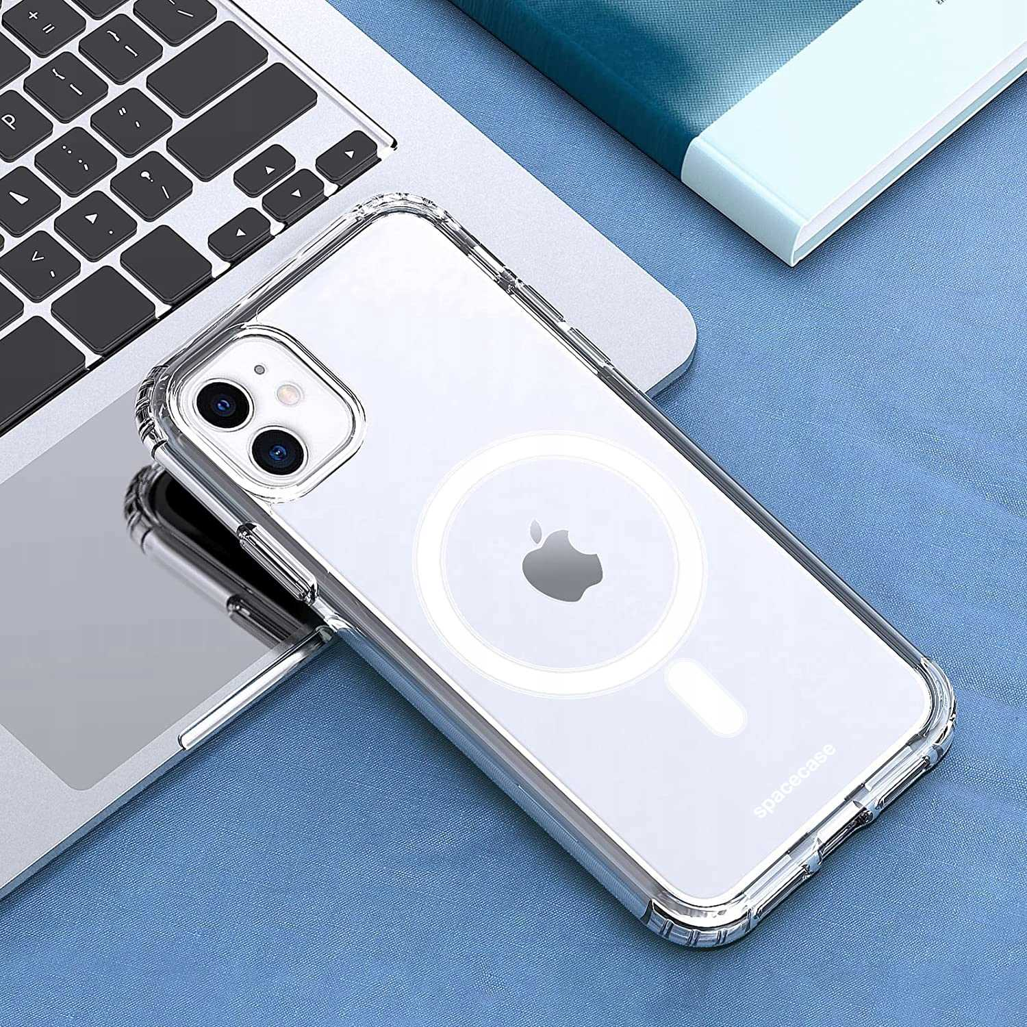 Przezroczyste etui na telefon z białym kółkiem, na klawiaturze laptopa na niebieskiej powierzchni.