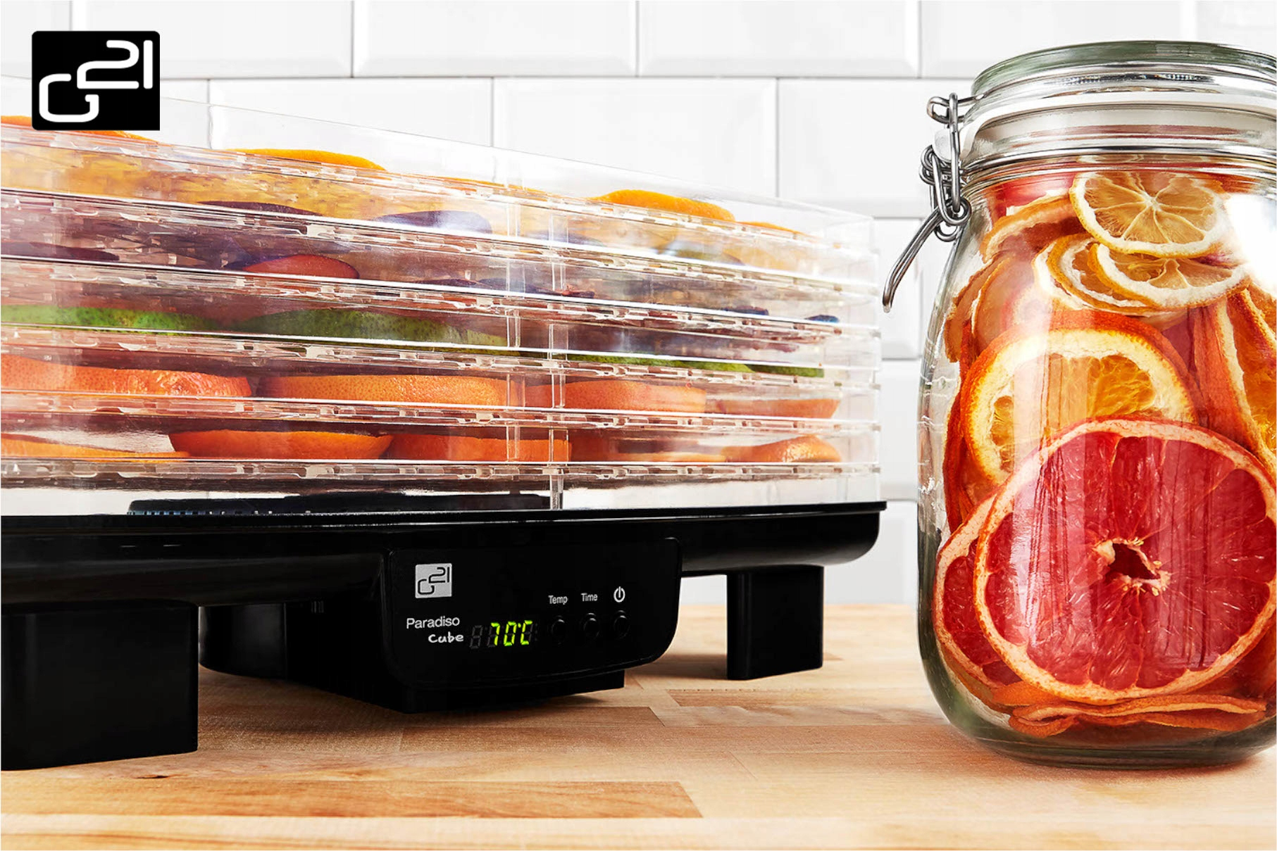 Suszarka do żywności z owocami. Słoik suszonych owoców. Białe tło z płytek. Drewniana powierzchnia.