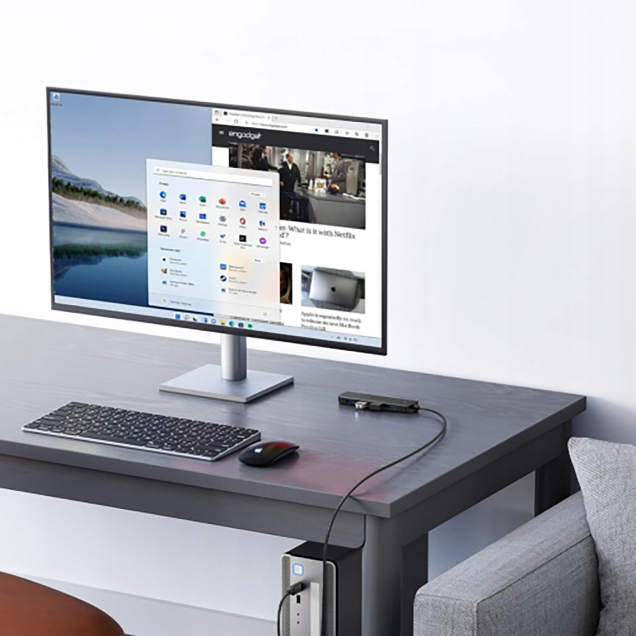 Una scrivania con monitor, tastiera, mouse e hub USB collegato a un computer.