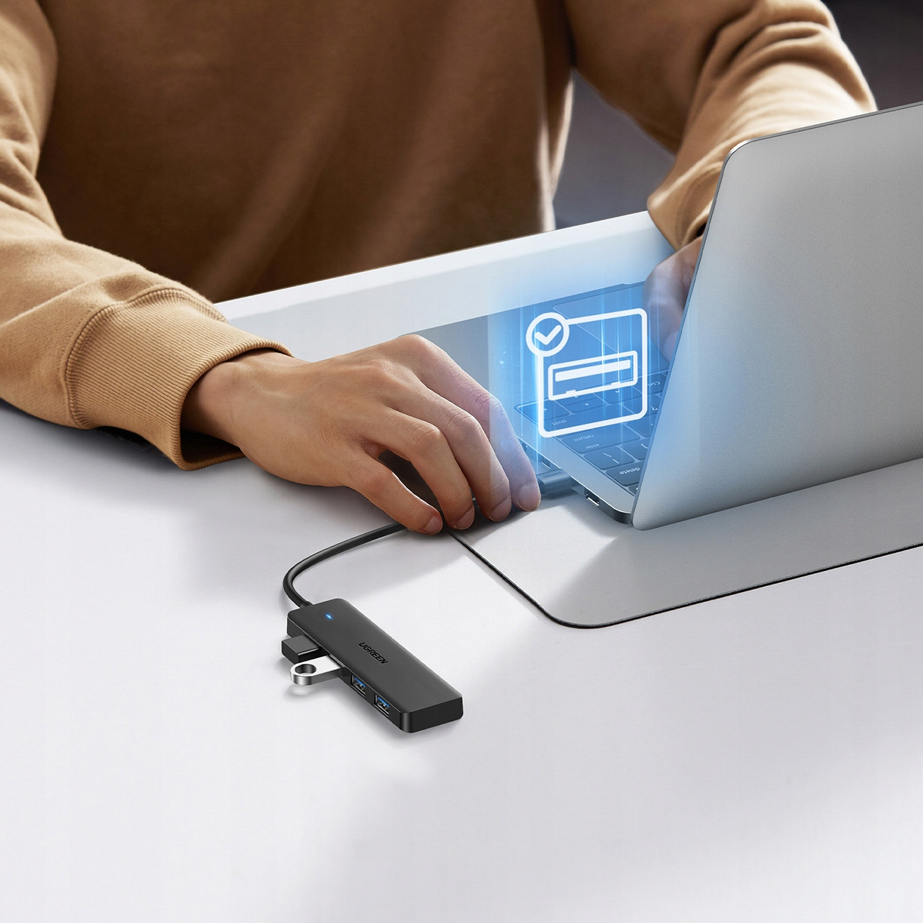 Una persona usa un laptop collegato a un hub USB nero. Un segno di spunta è sullo schermo.