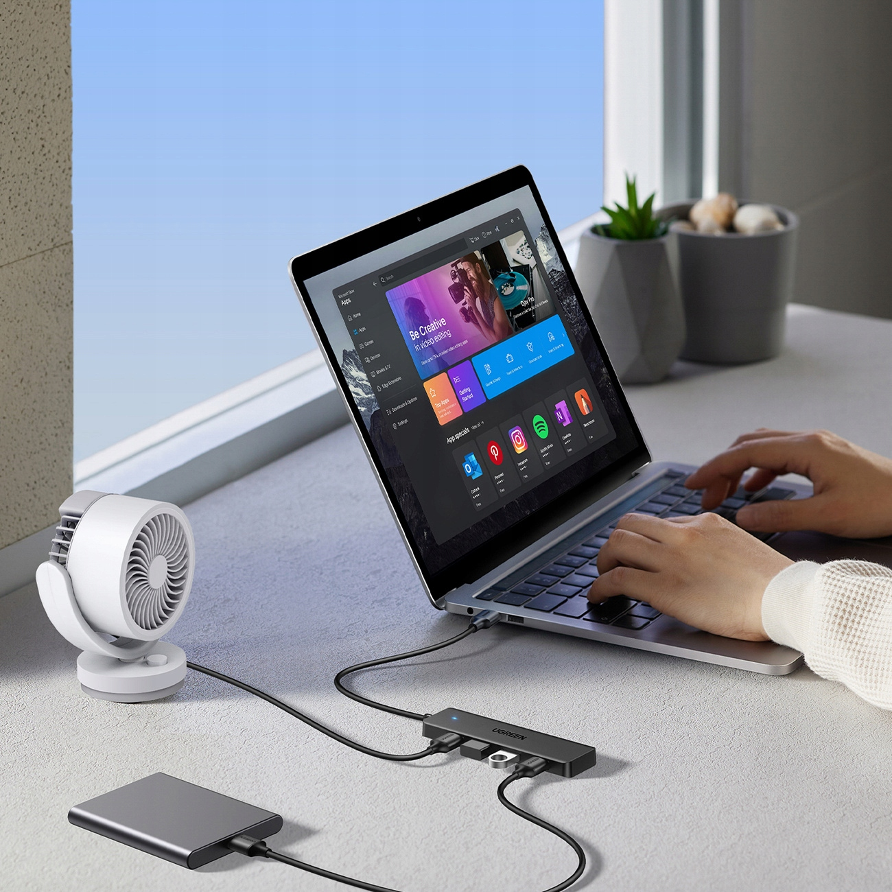 Un laptop collegato a un hub USB e ad altri dispositivi. Una ventola è accanto al laptop.
