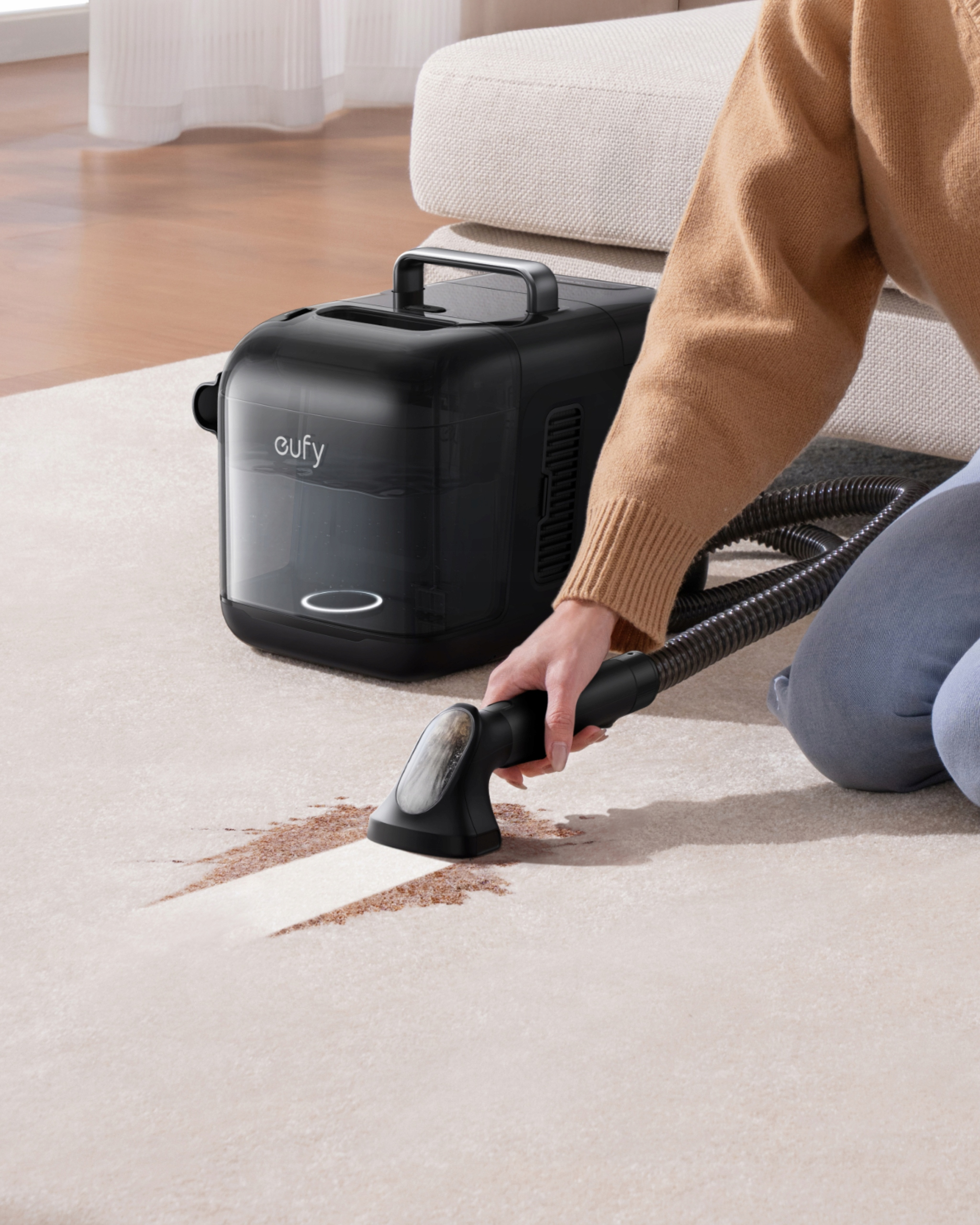 Osoba używająca czarnego urządzenia czyszczącego na dywanie z plamą. Czarne urządzenie na dywanie.