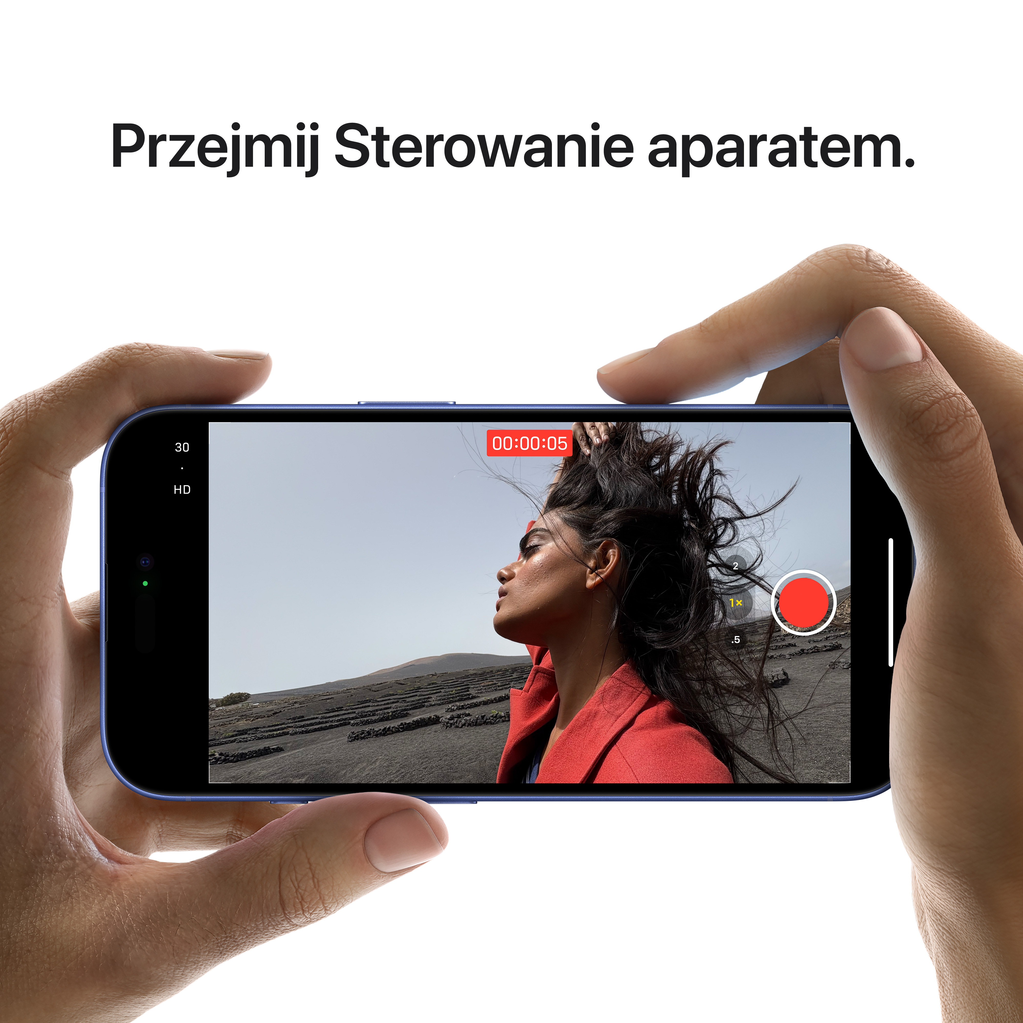 Eine Person hält ein blaues iPhone und zeigt die Aufnahmeschnittstelle. Ein roter Aufnahme-Button ist sichtbar, der Hintergrund ist dunkel.