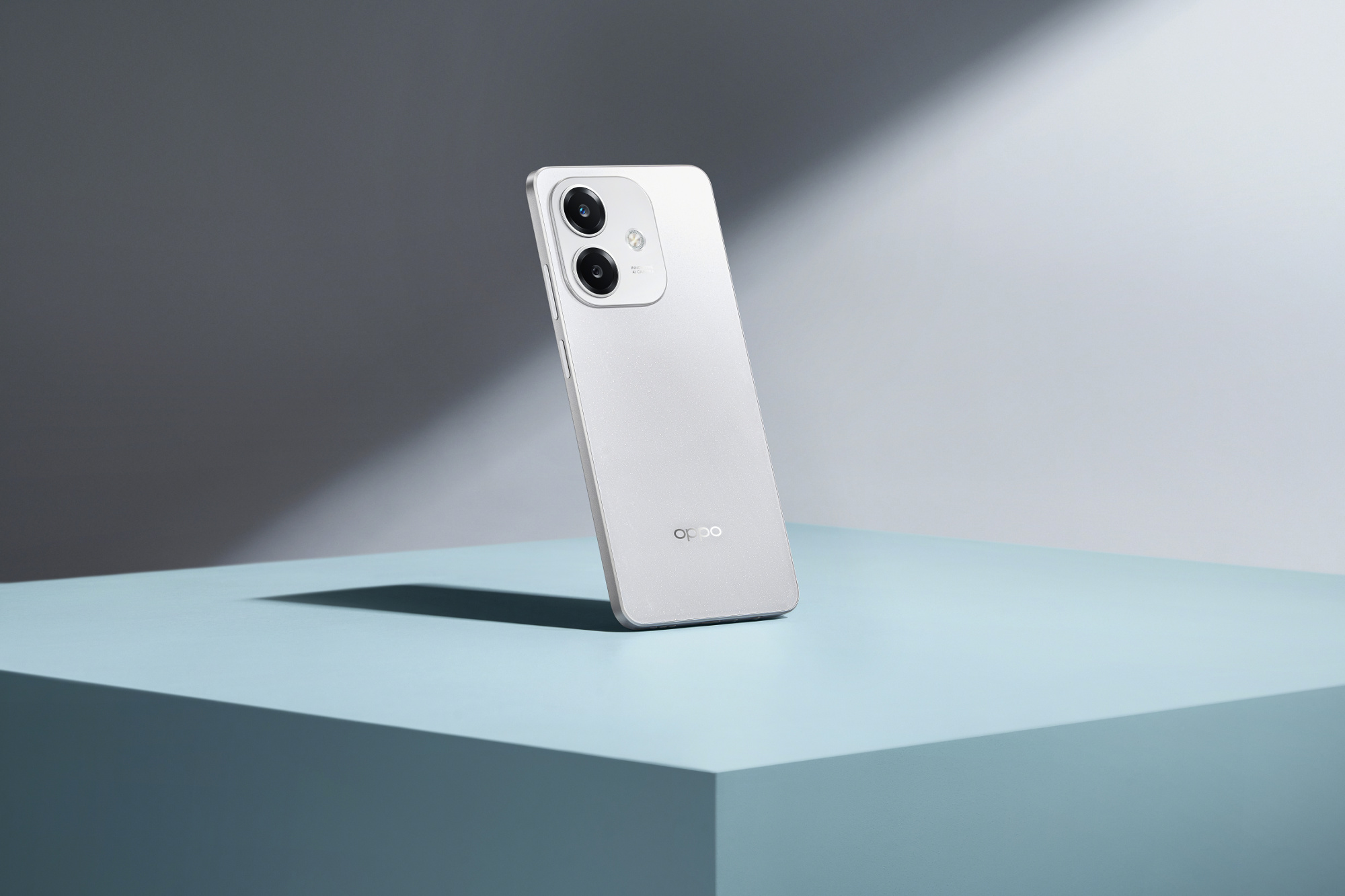 Teléfono Oppo blanco sobre una superficie azul. El teléfono está ligeramente inclinado.
