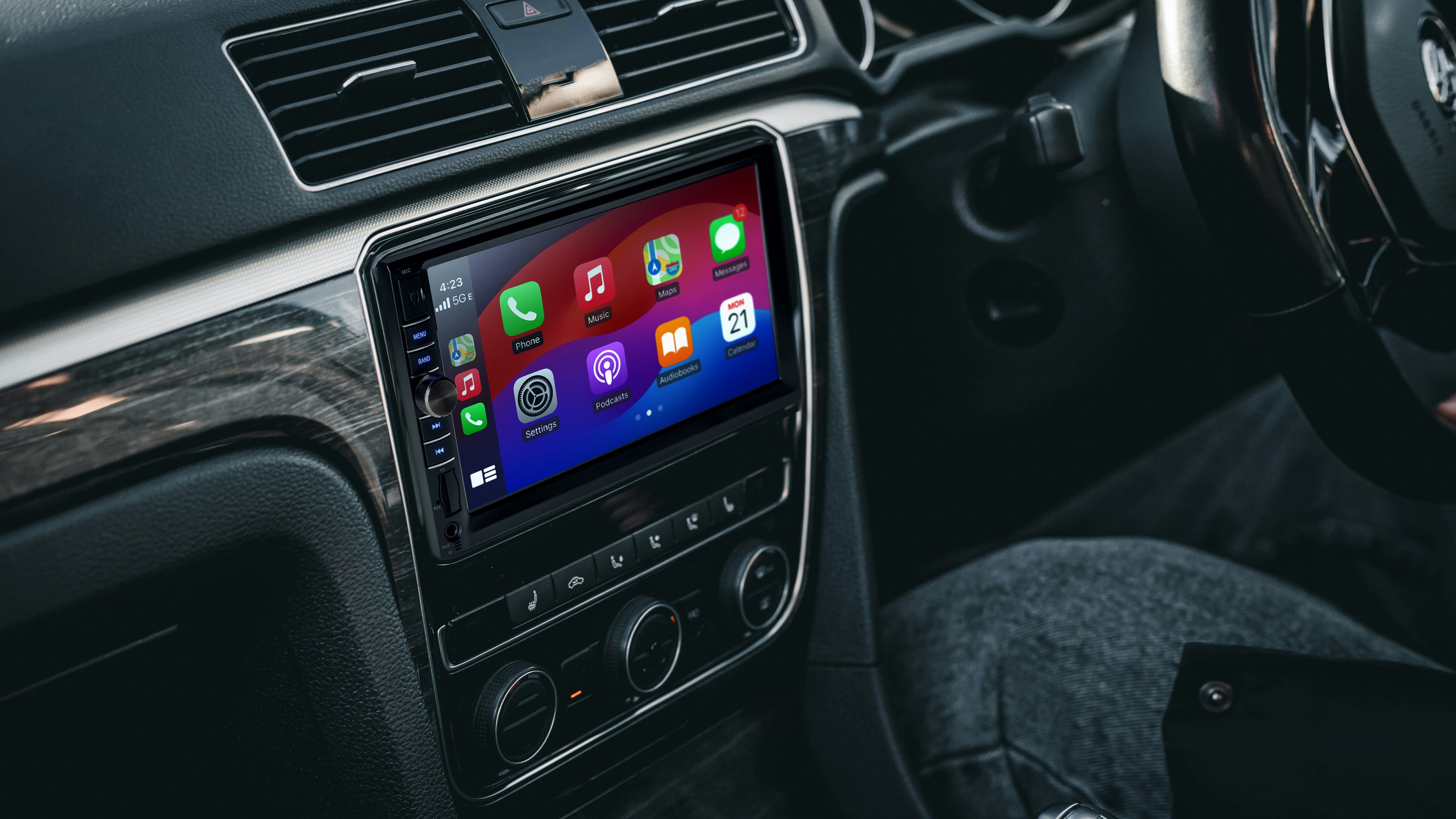 Car interior with a digital touchscreen in the dashboard displaying app icons. A person is visible on the right.