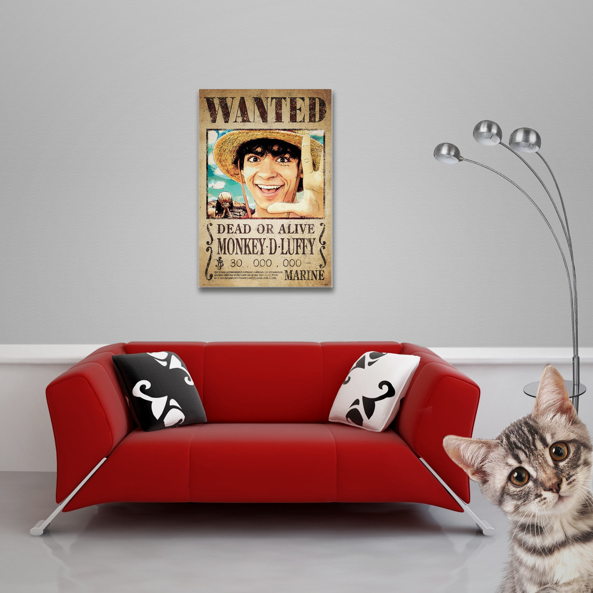 Ein gerahmtes Wanted-Poster von Monkey D. Luffy an einer Wand, ein rotes Sofa, eine Katze und eine Lampe.