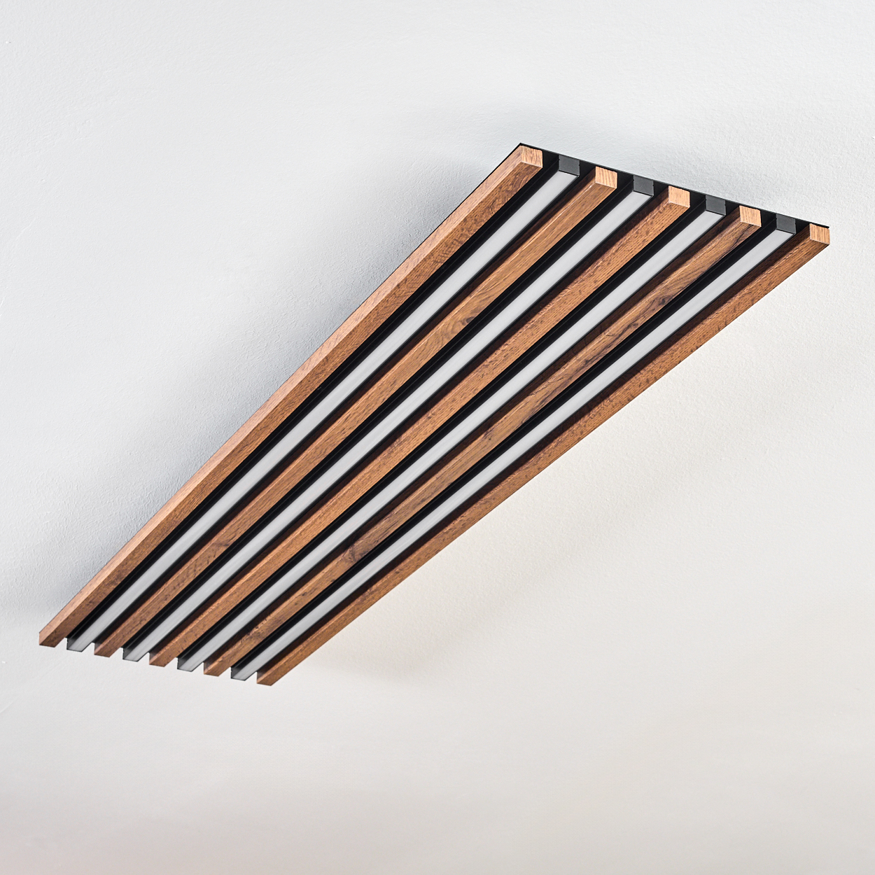 Rechteckige Deckenleuchte aus Holz und Schwarz mit weißer Beleuchtung zwischen den Balken. Weiße Decke.