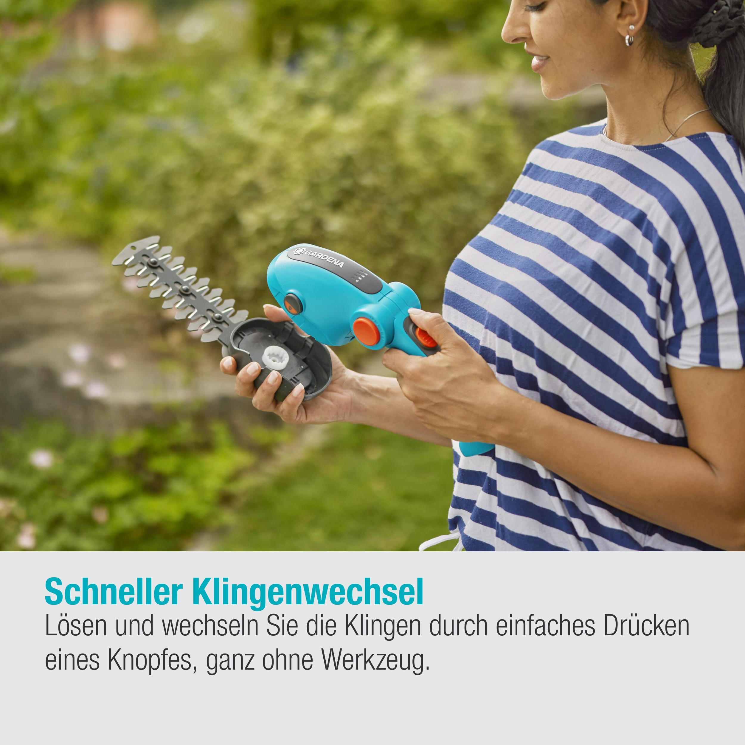 Eine Frau hält eine hellblaue und orangefarbene Heckenschere mit abgenommener Klinge. Blau-weiß gestreiftes Hemd.
