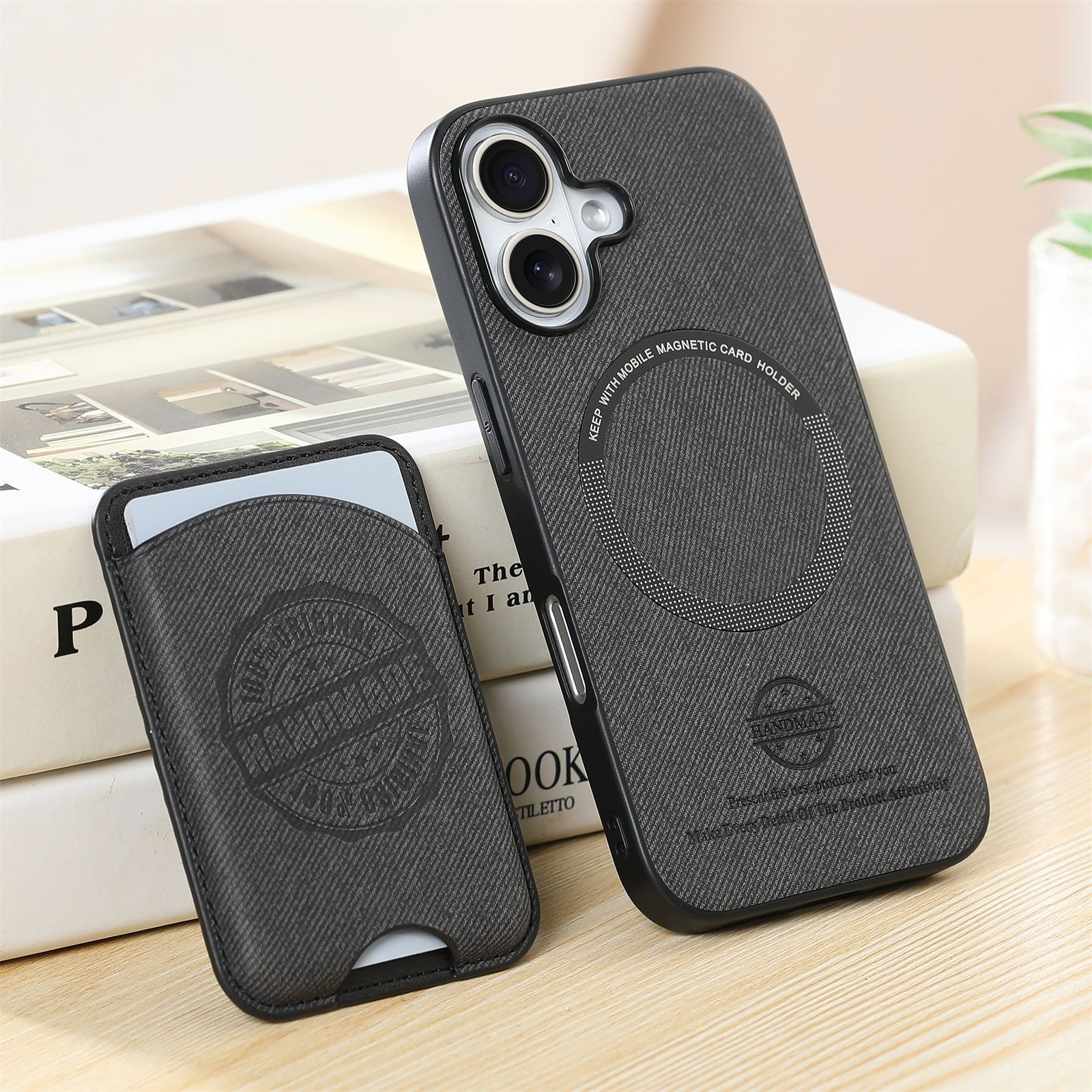 Una custodia grigia per telefono e un porta carte. La custodia ha un supporto magnetico. Libri sullo sfondo.