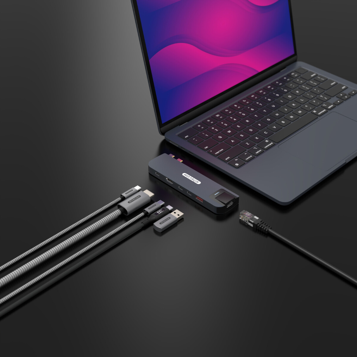 Laptop, hub USB-C e cavi su una superficie nera. I cavi si collegano all'hub e al laptop. Cavo Ethernet.