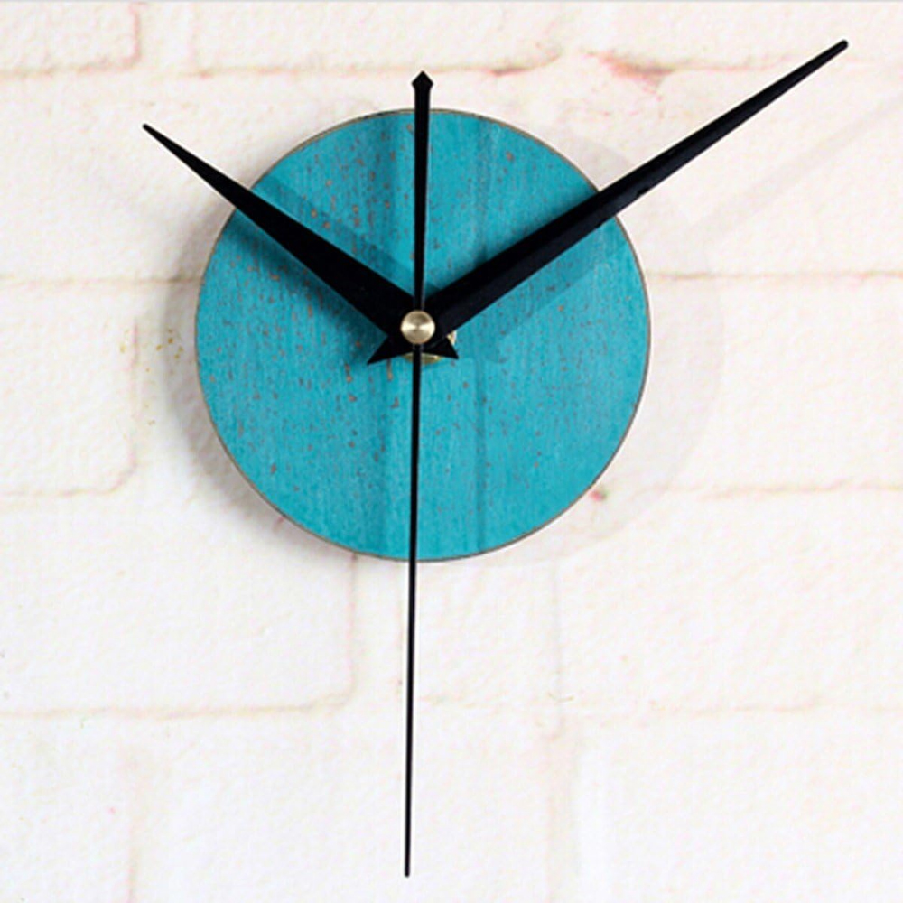 Eine Uhr mit einem blauen, strukturierten Zifferblatt und schwarzen Zeigern. Der Hintergrund ist eine weiße Backsteinmauer.