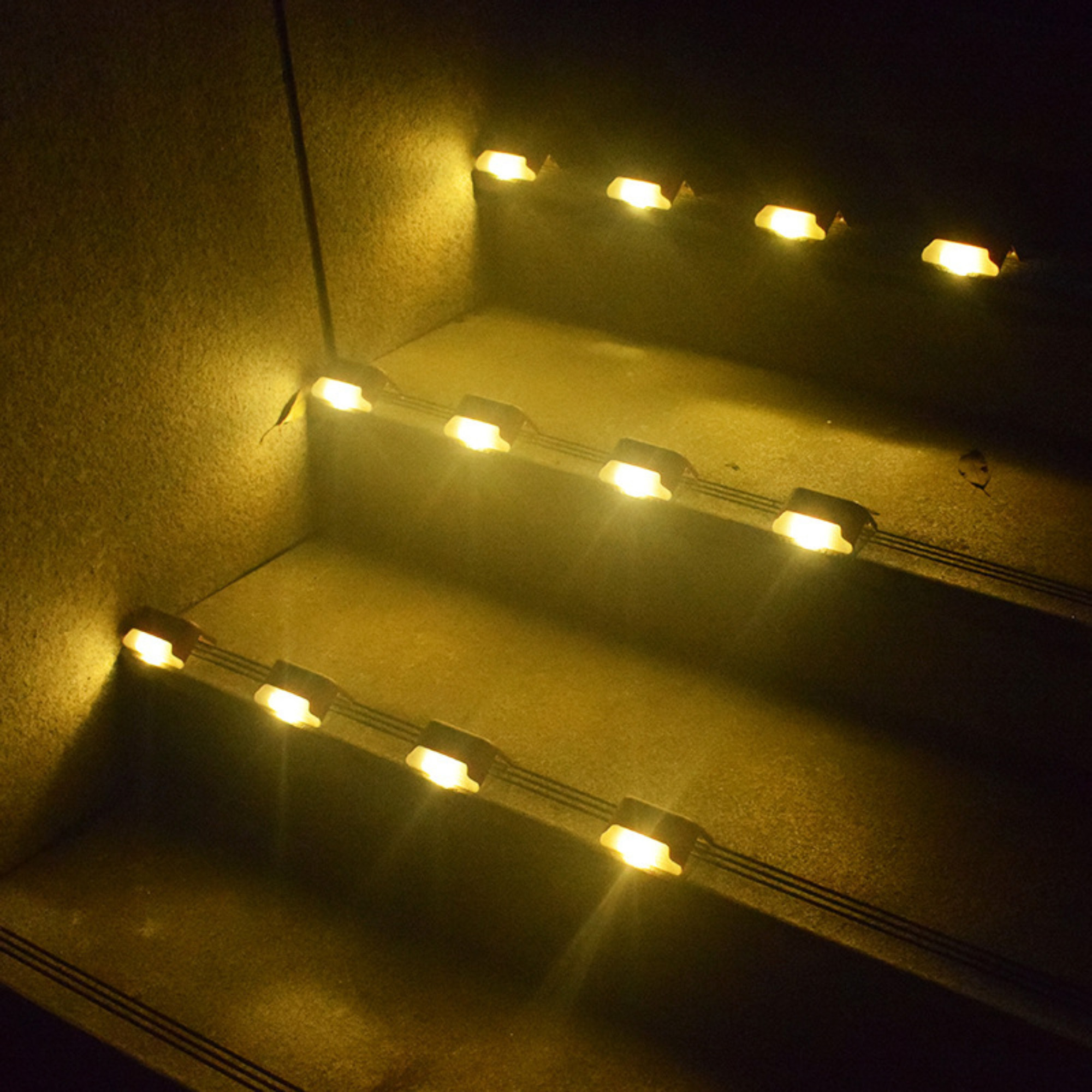 Treppe mit kleinen Lichtern auf jeder Stufe, die die Stufen beleuchten. Die Wände sind hellbraun.