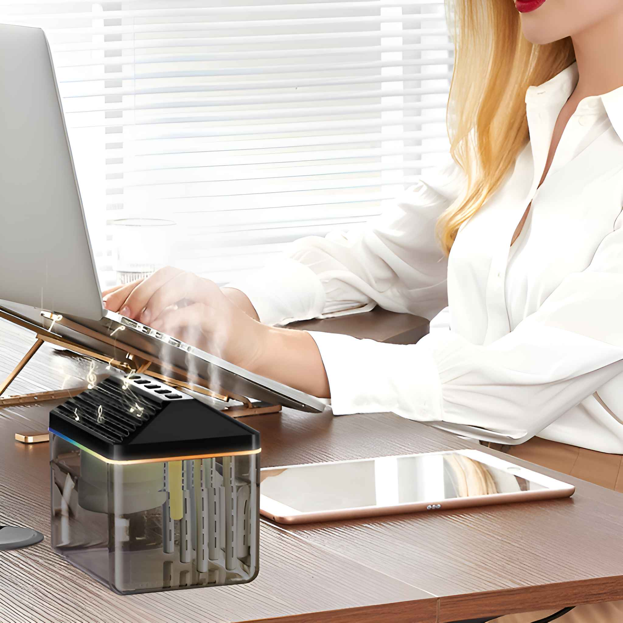 Eine Frau arbeitet an einem Laptop neben einem Luftbefeuchter. Der Befeuchter hat einen transparenten Körper.
