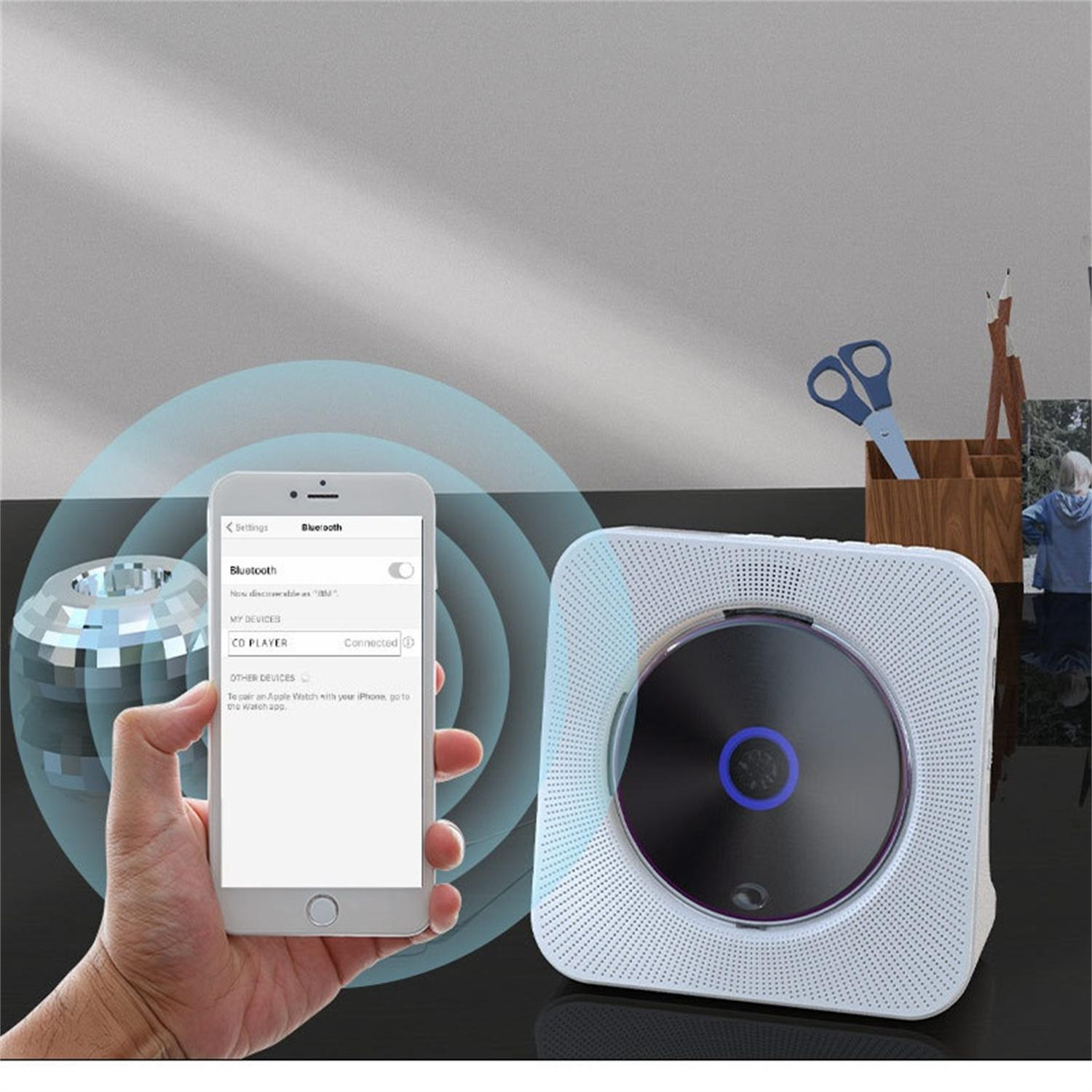 Eine Hand, die ein Telefon mit Bluetooth-Verbindung zu einem weißen CD-Player hält.