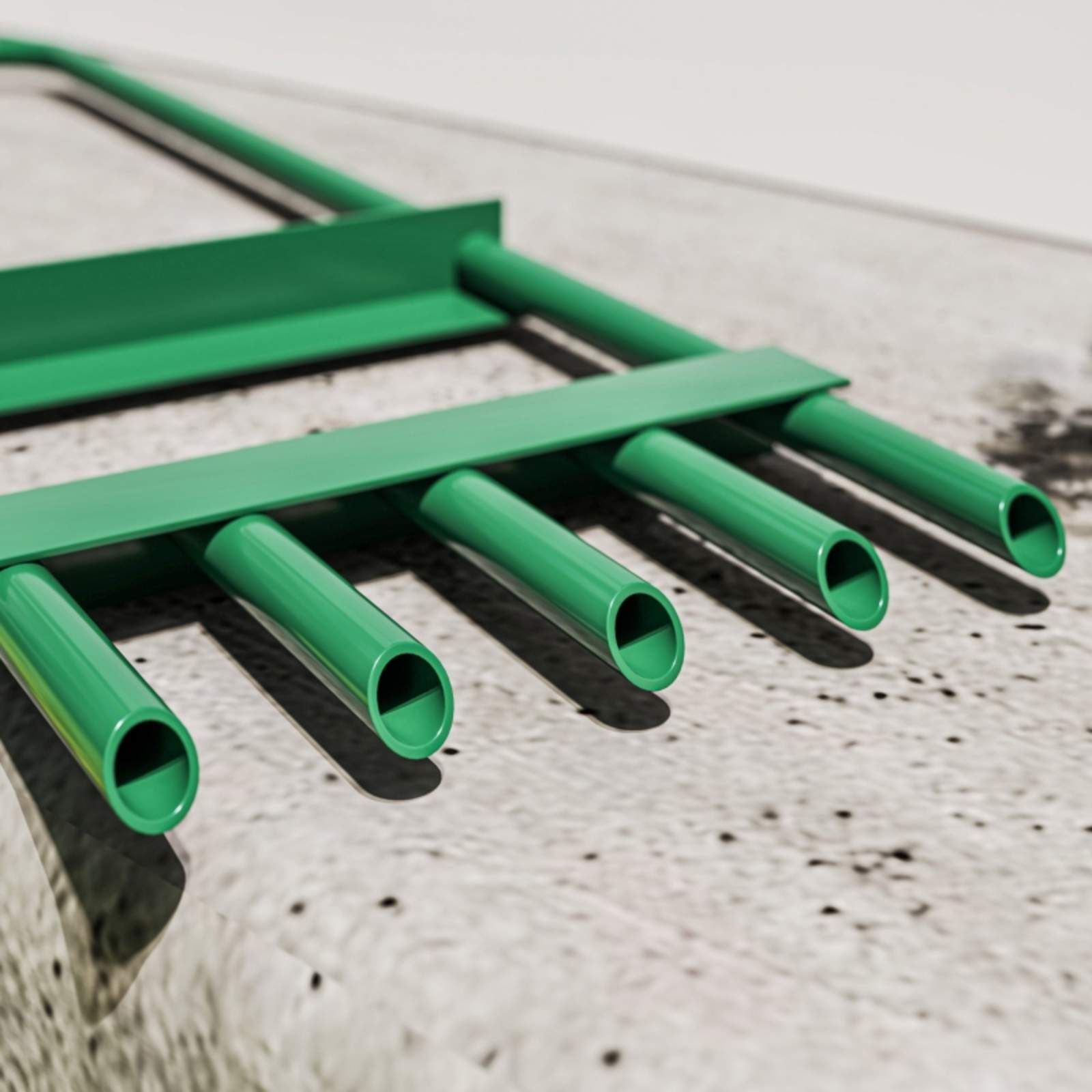 Grüne Rohre und Verbinder auf einer Betonoberfläche, Nahaufnahme.