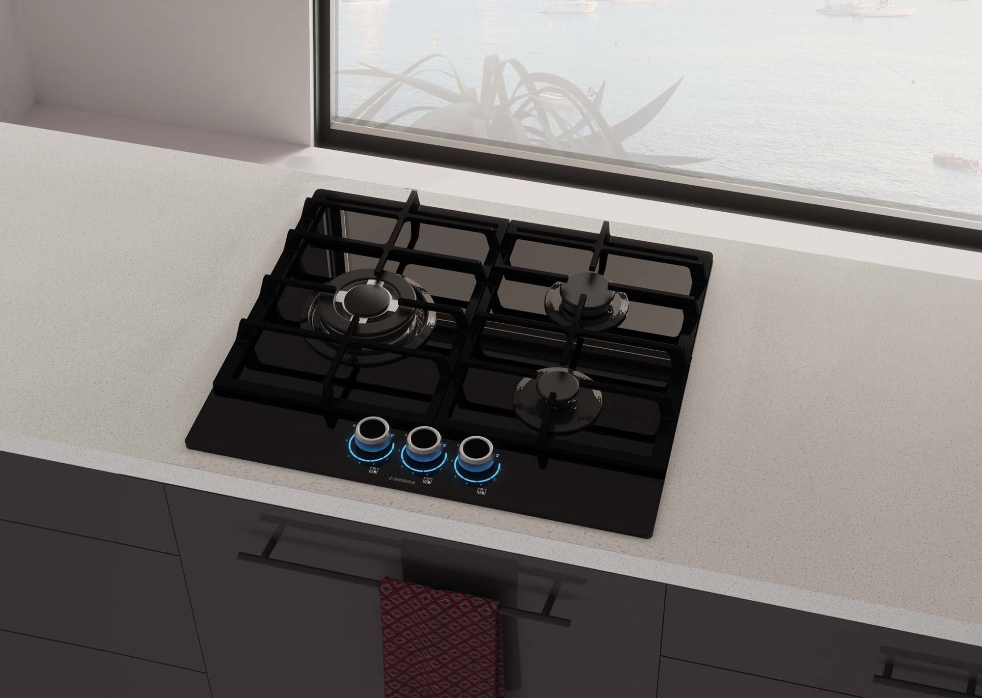 Czarna płyta gazowa stoi na białym blacie w pobliżu okna z widokiem na ocean i łodzie.