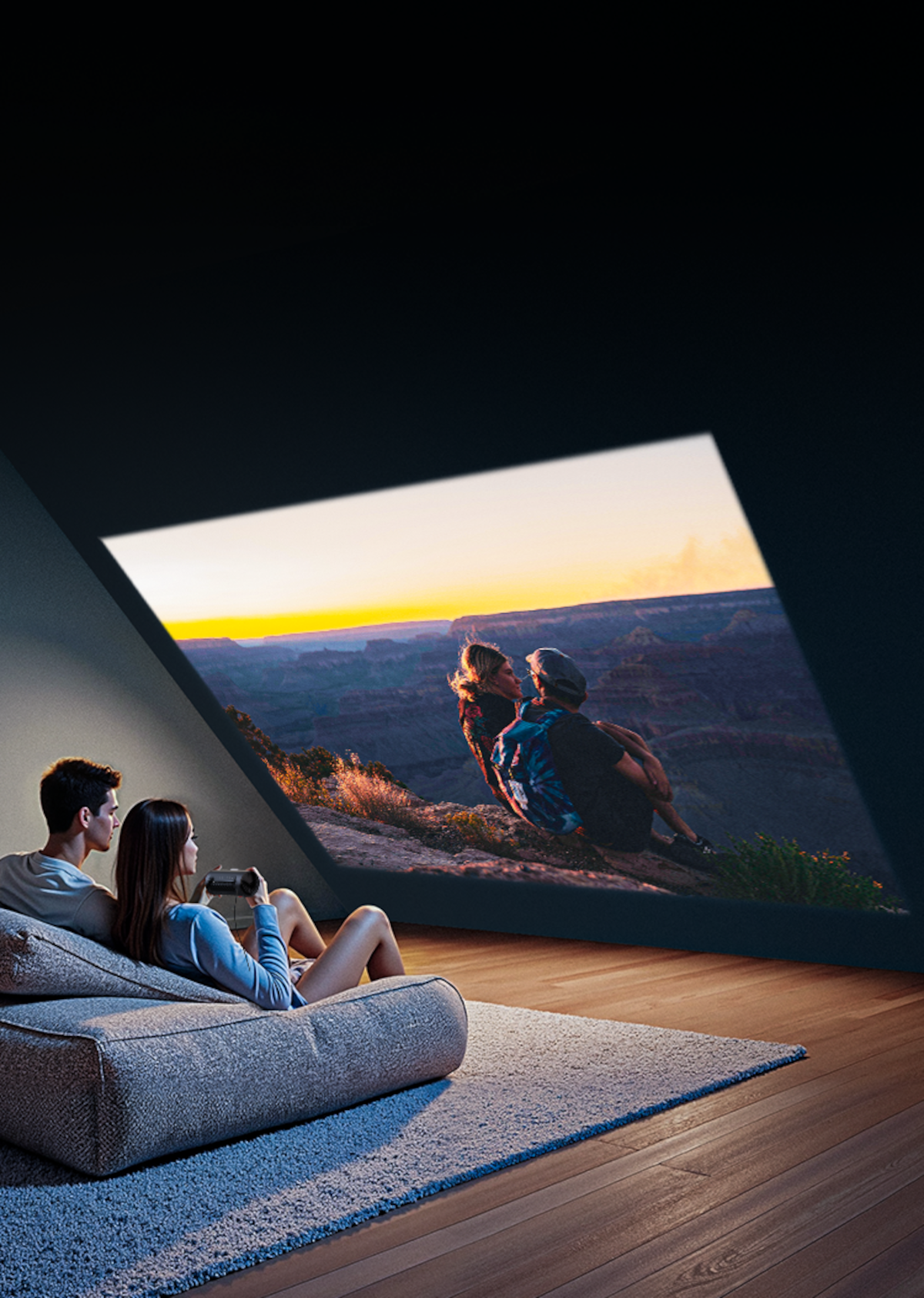Para ogląda projekcję zachodu słońca na ścianie, siedząc na szarej pufie.