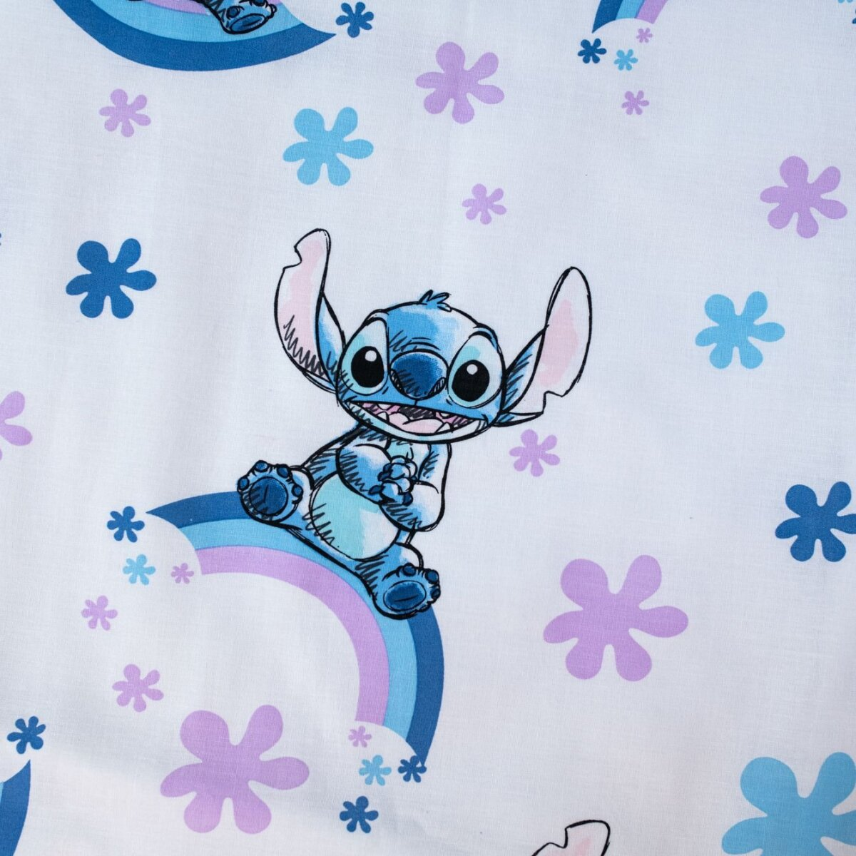 Stitch-Cartoon auf weißem Hintergrund. Regenbogen, Blumen und Stitch auf einem Bettlaken.