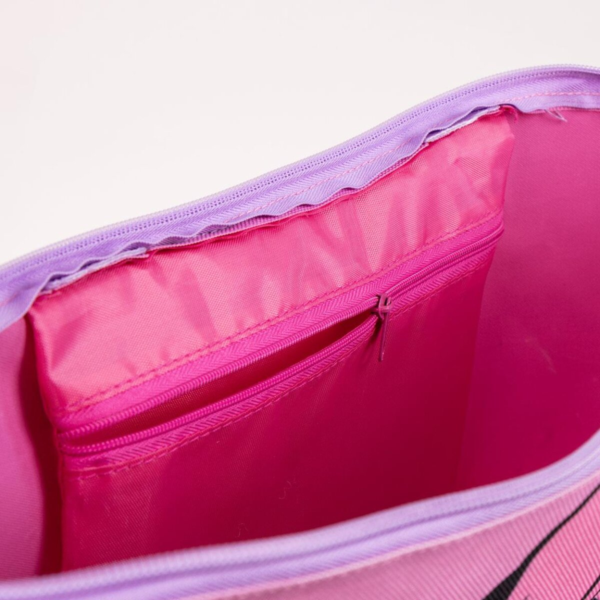 Primer plano del interior de una bolsa tote rosa de Minnie Mouse. Dentro hay un pequeño bolsillo rosa con cremallera.