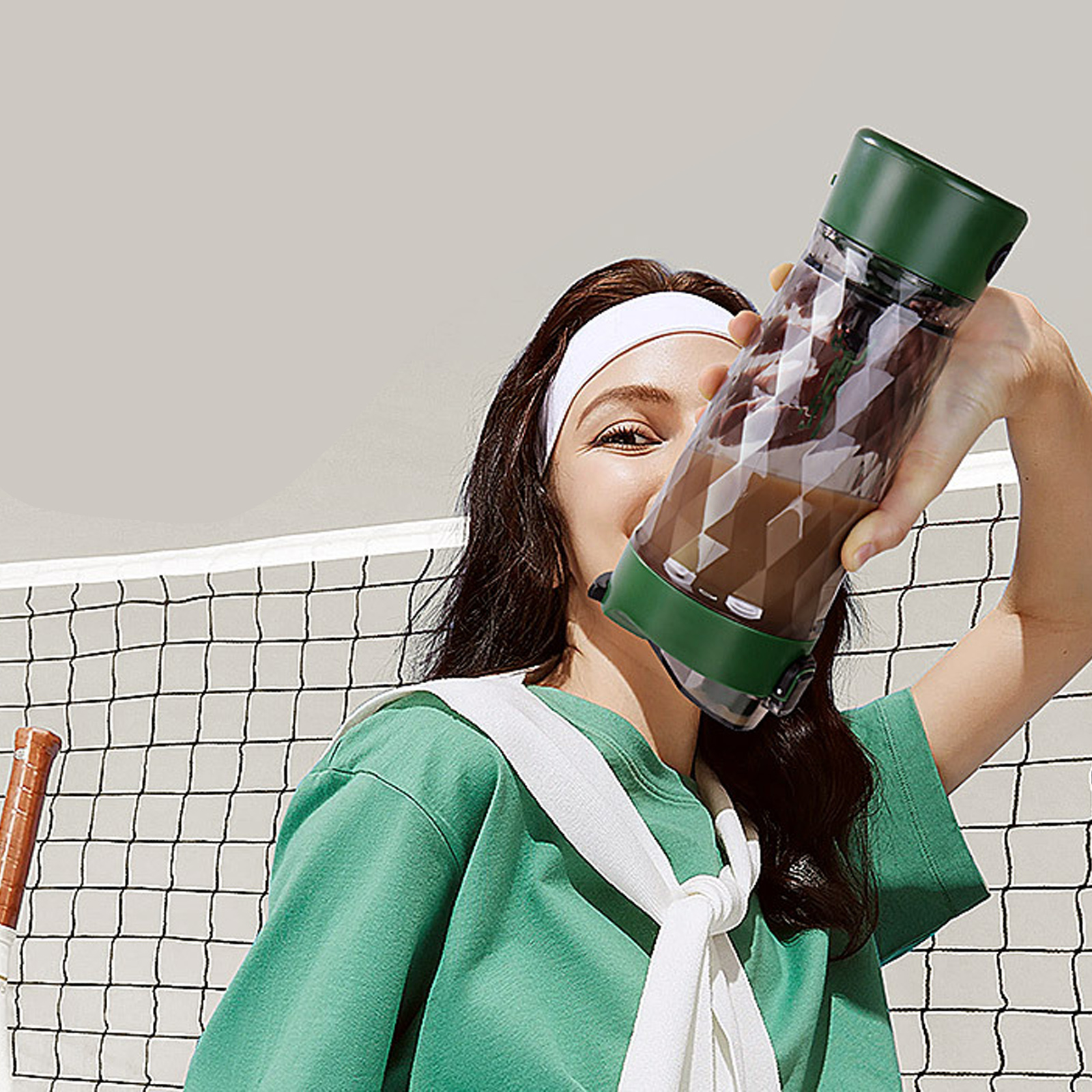 Eine Frau trinkt im Freien aus einer grünen und transparenten Shaker-Flasche.