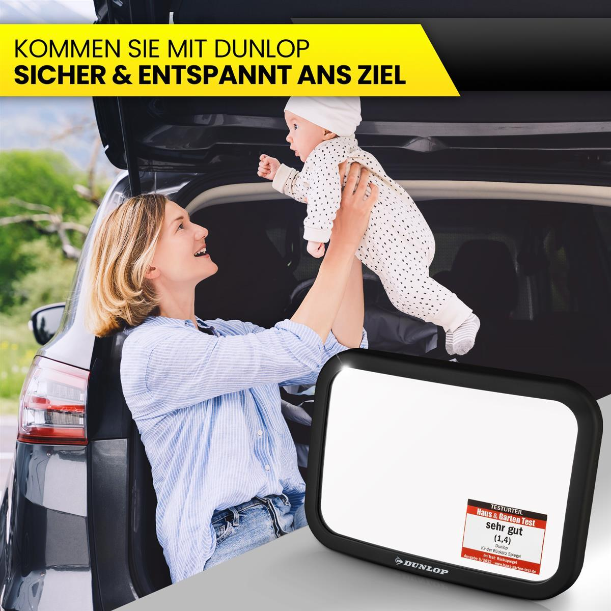 Eine Frau hält ein Baby vor einem Auto, mit einem Rückspiegel.