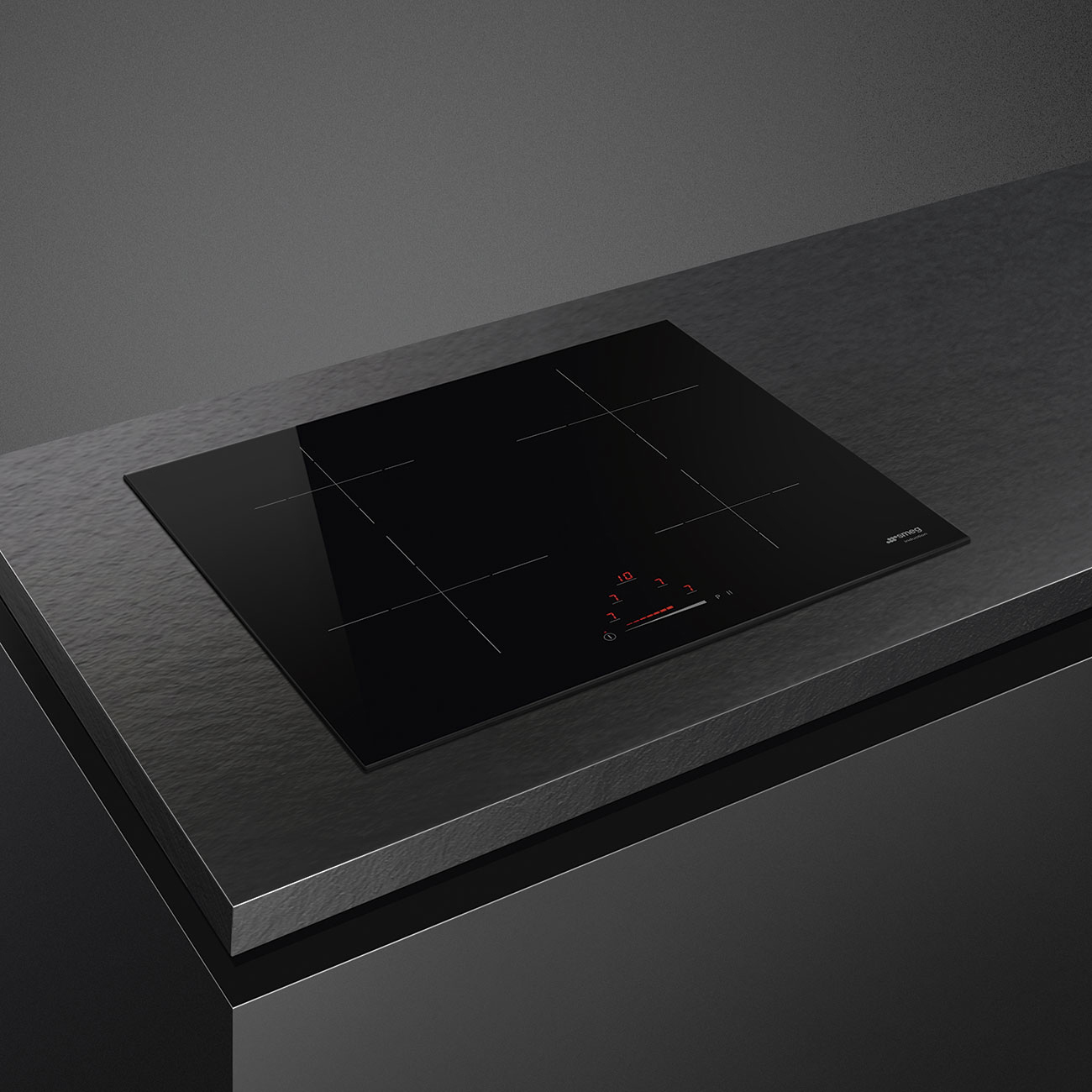 Un piano cottura a induzione Smeg con quattro zone di cottura e comandi a sfioramento è esposto su un piano di lavoro scuro.