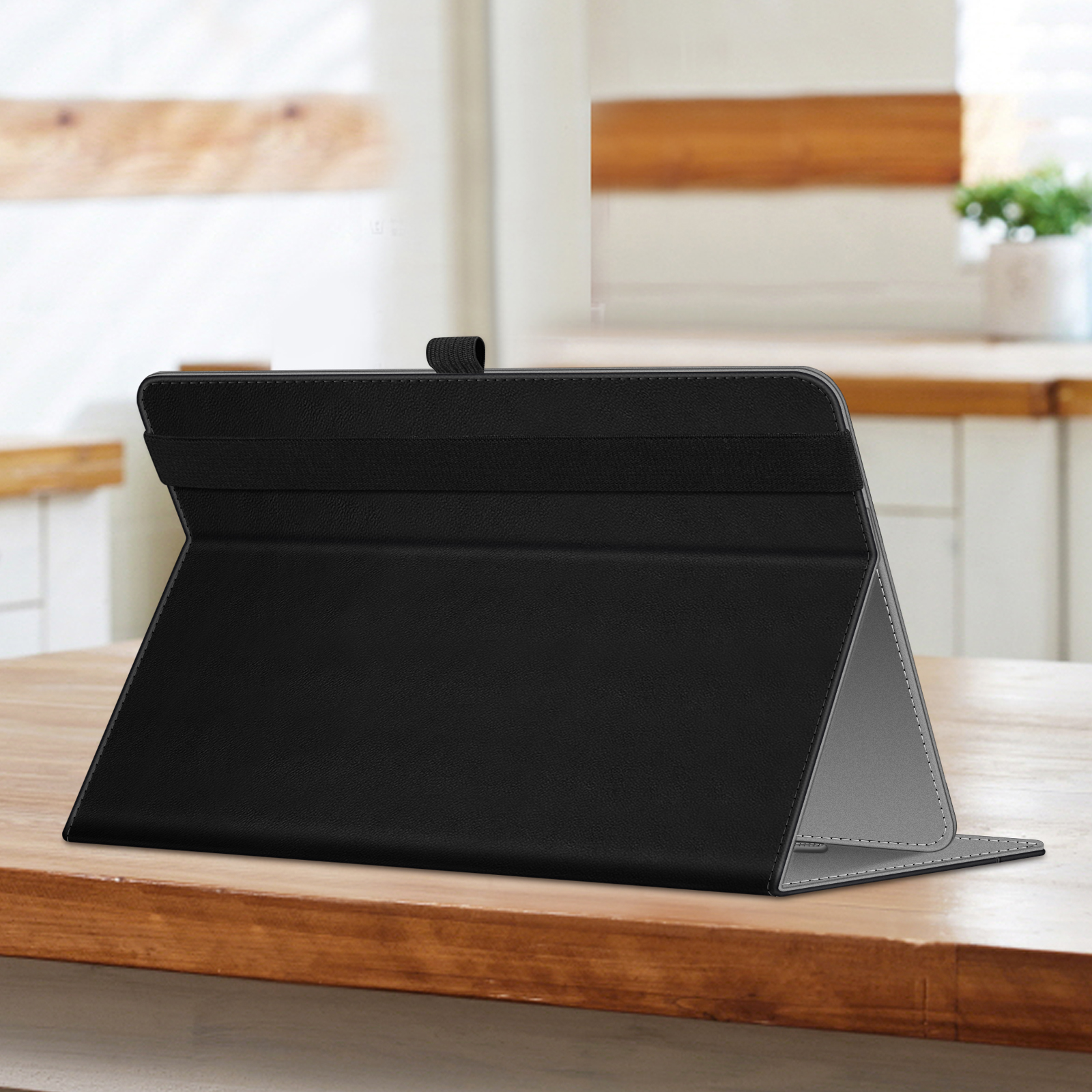 Schwarze Tablethülle, geöffnet auf einem Holztisch. Die Hülle ist geöffnet aufgestellt. Küchenhintergrund.