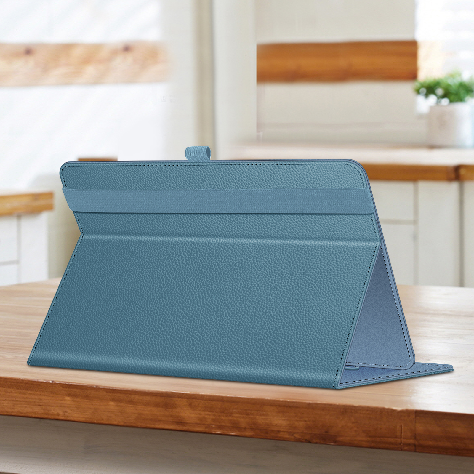 Eine blaue Tablet-Hülle, die auf einem Holztisch zu einem Ständer gefaltet ist, mit einer Küche im Hintergrund.