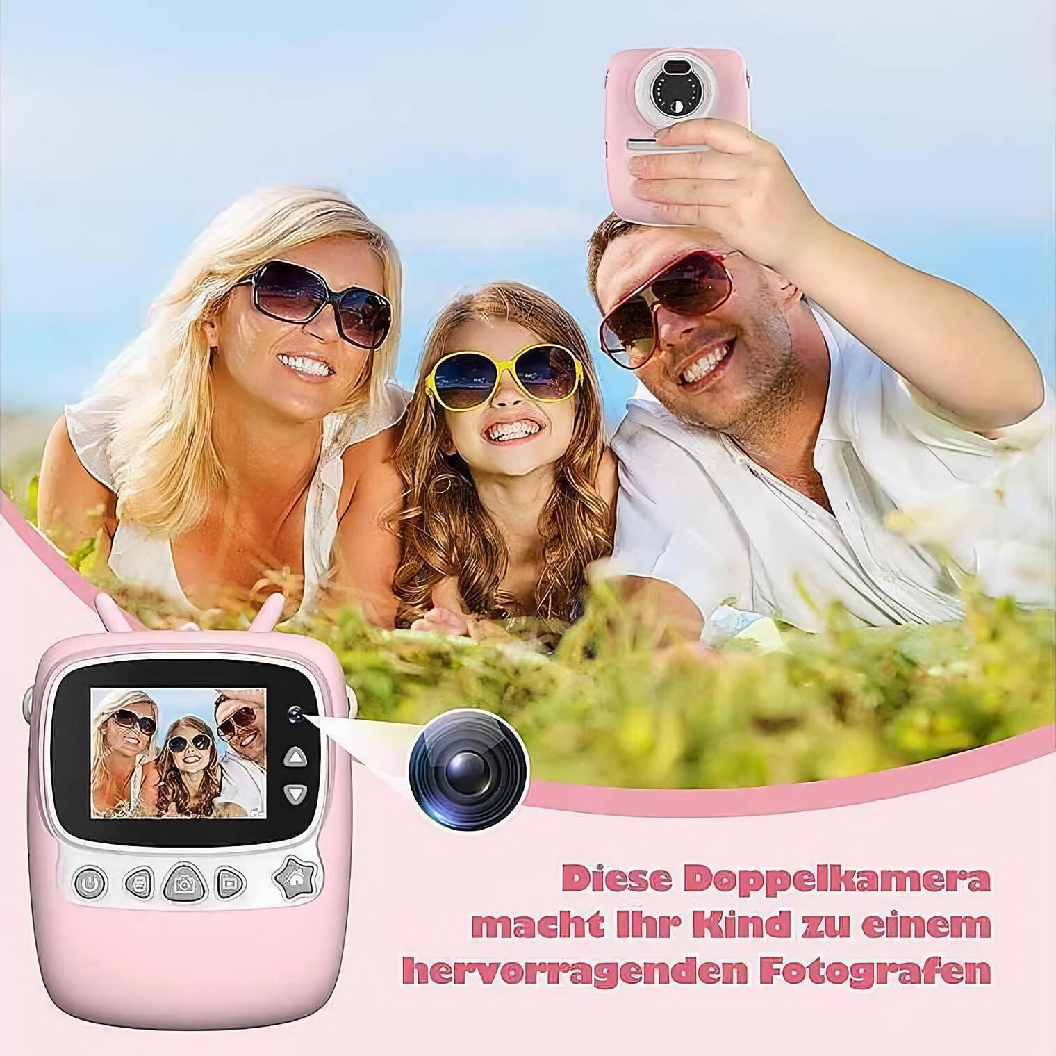 Eine Familie macht ein Selfie mit einer rosa Kamera auf einem Grashügel unter blauem Himmel.