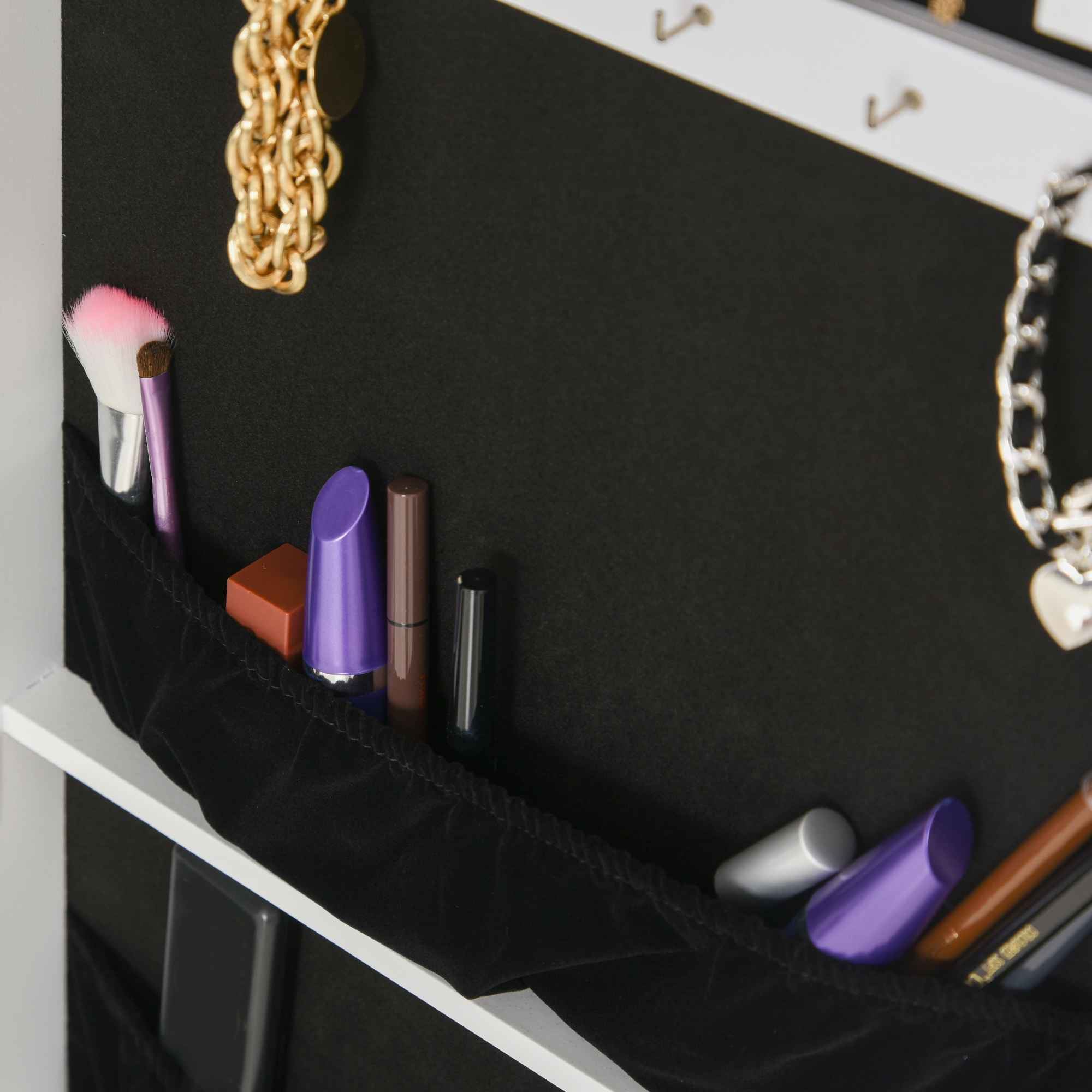 Nahaufnahme eines schwarzen Aufbewahrungsorganizers, gefüllt mit Make-up-Artikeln und Schmuck.