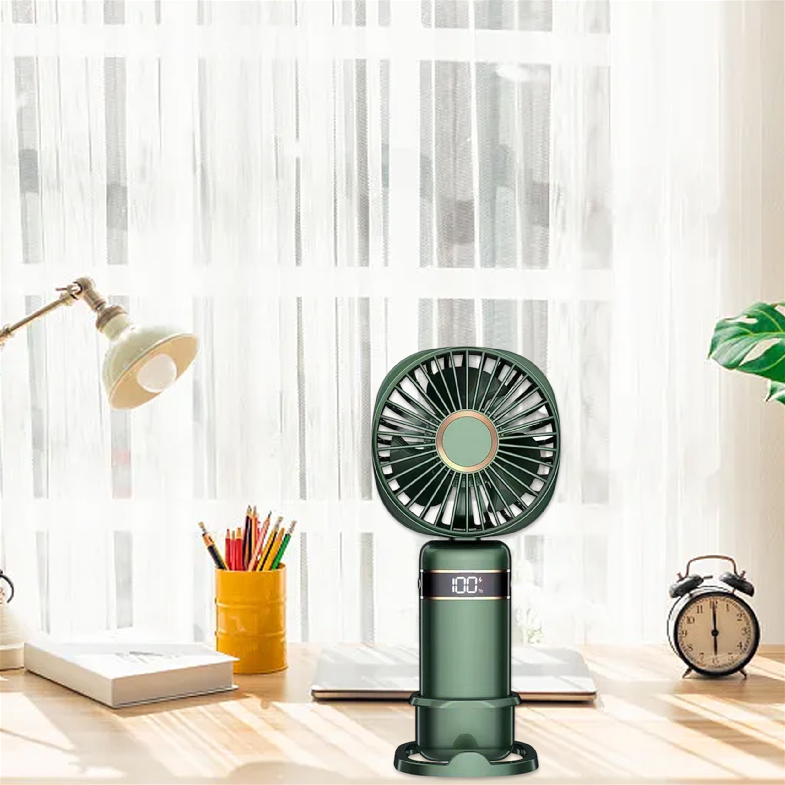 Ein grüner tragbarer Ventilator mit Digitalanzeige, Bleistifte in einem gelben Becher und eine Schreibtischlampe.