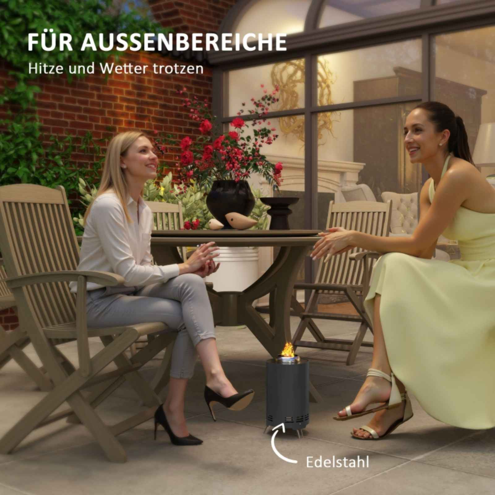 Zwei Frauen sitzen in der Nähe einer Feuerstelle, eine in einem gelben Kleid. Ein Tisch, Stühle und Pflanzen.