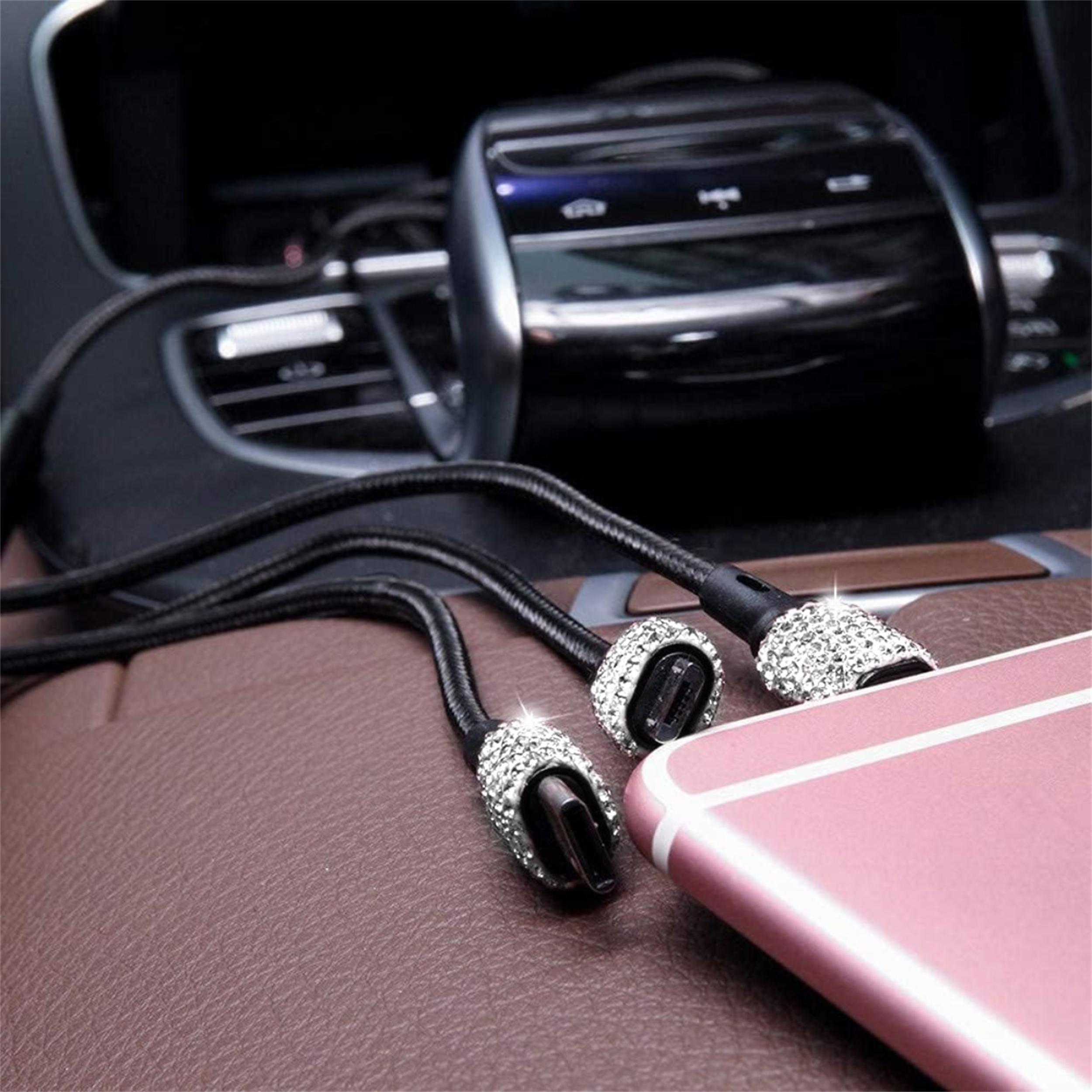 Schwarzes USB-Ladekabel mit mehreren Spitzen. Spitzen sind mit Kristallen verziert. Das Kabel liegt auf einem Telefon.