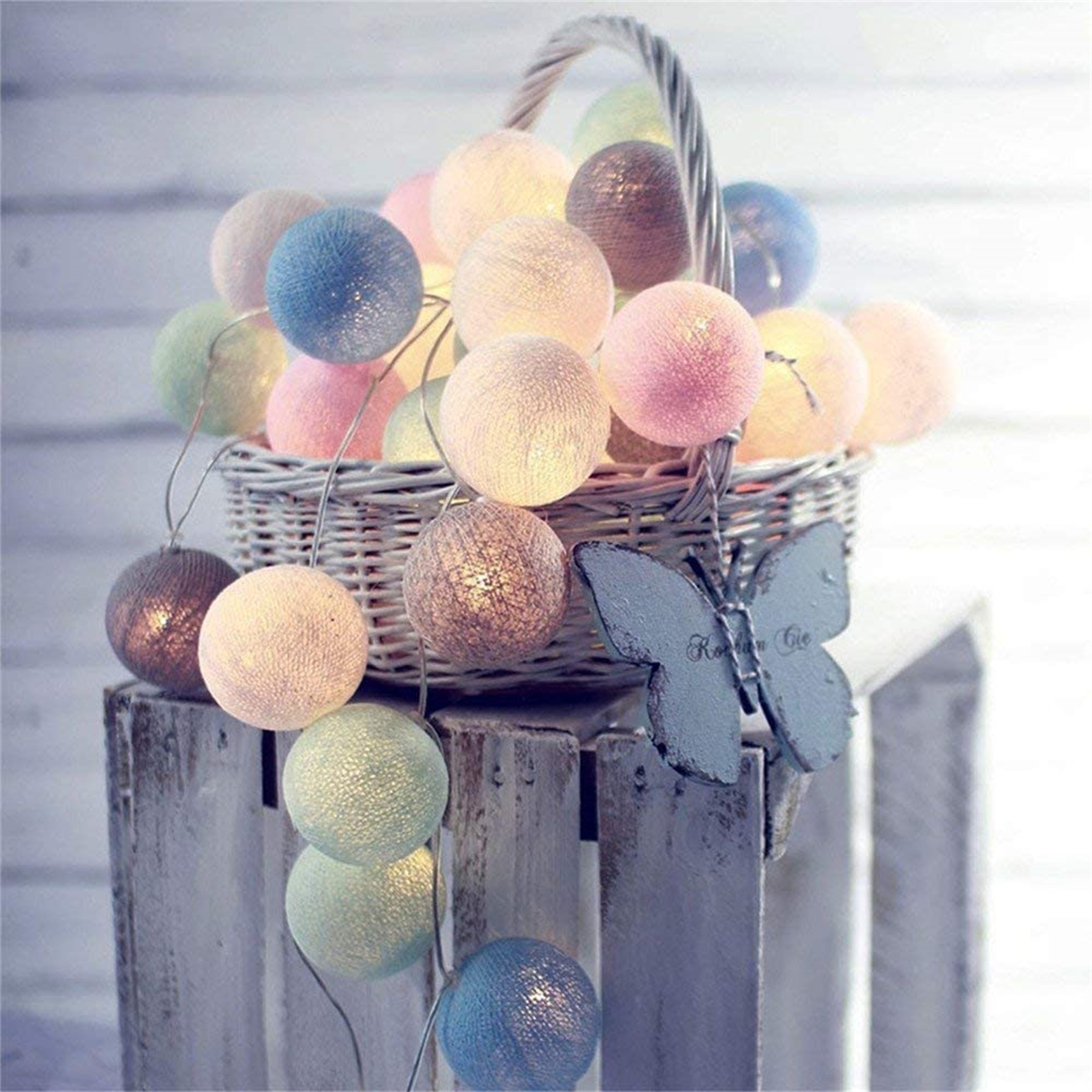 Lichterkette mit bunten Kugeln in einem Korb mit Schmetterlingsdekoration.