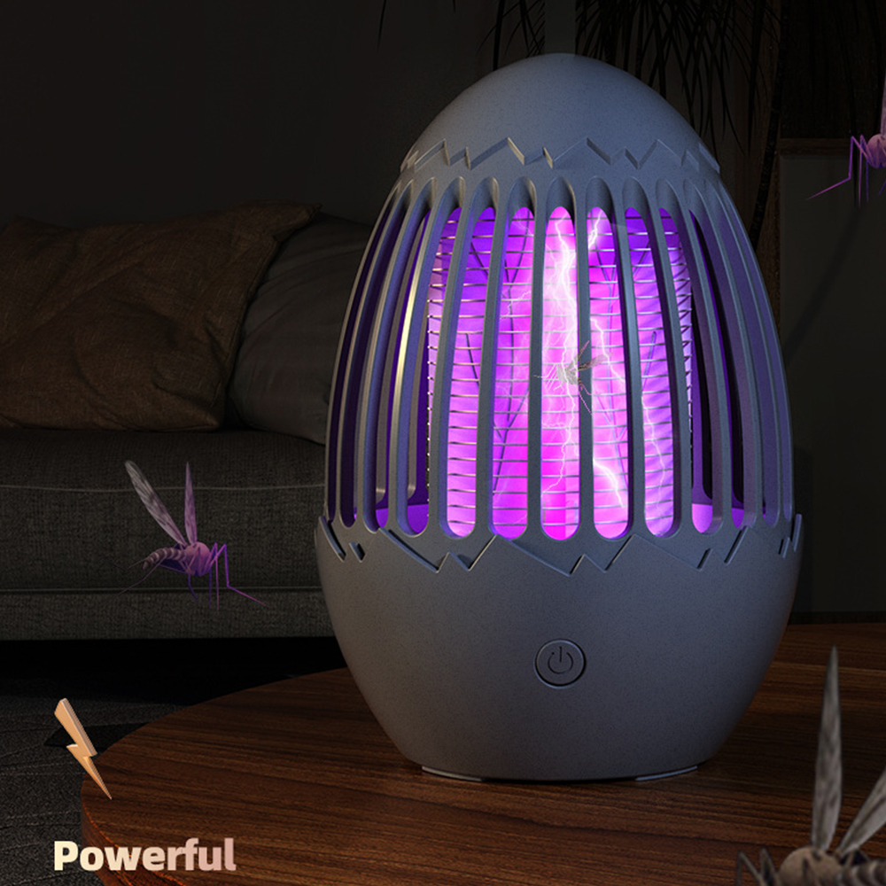 Eiförmige Mückenfalle mit lila Licht. Mücken fliegen in der Nähe, auf einem Holztisch.