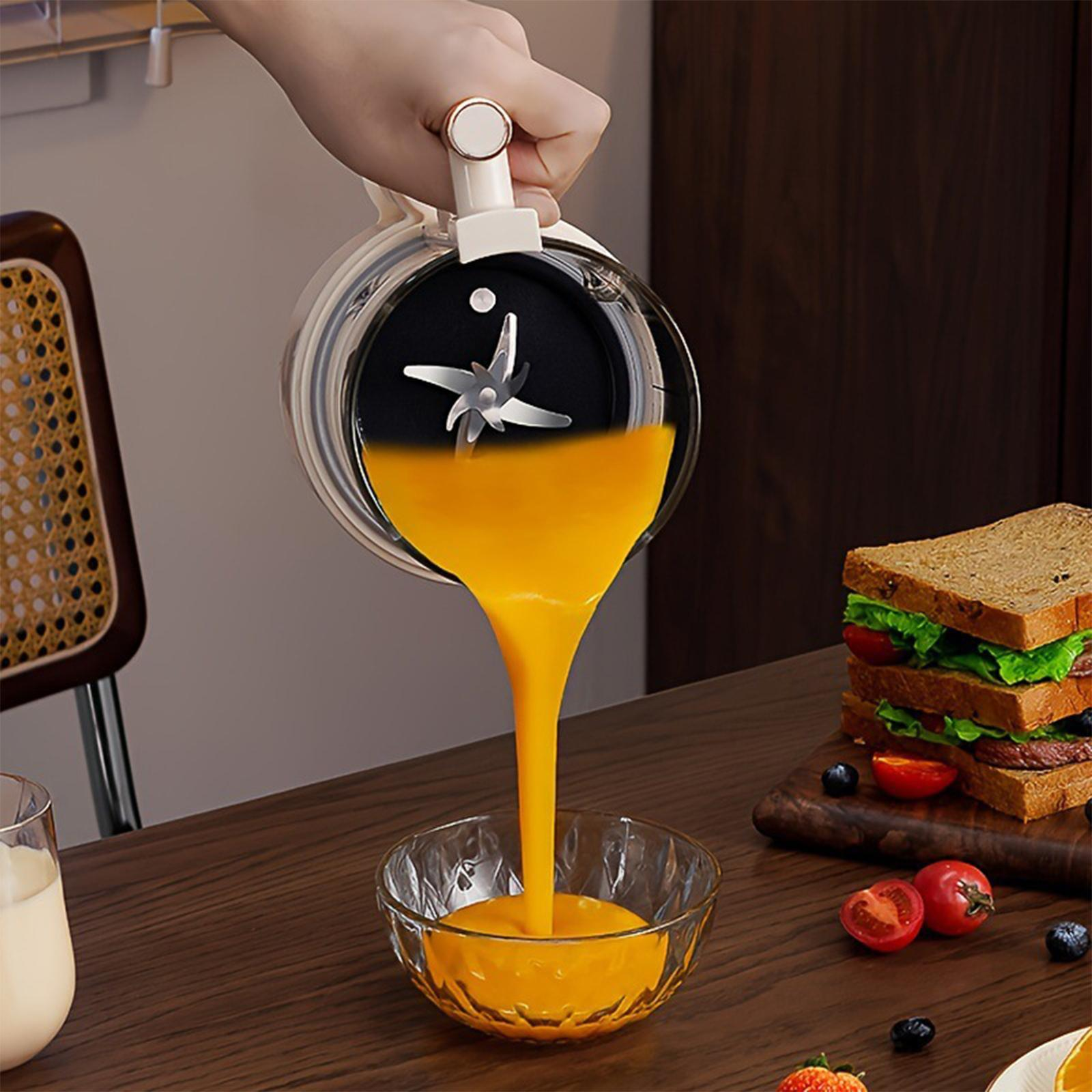 Ein Mixer gießt Orangensaft in eine Glasschüssel. Auf einem Holzbrett liegen Sandwiches und Tomaten.