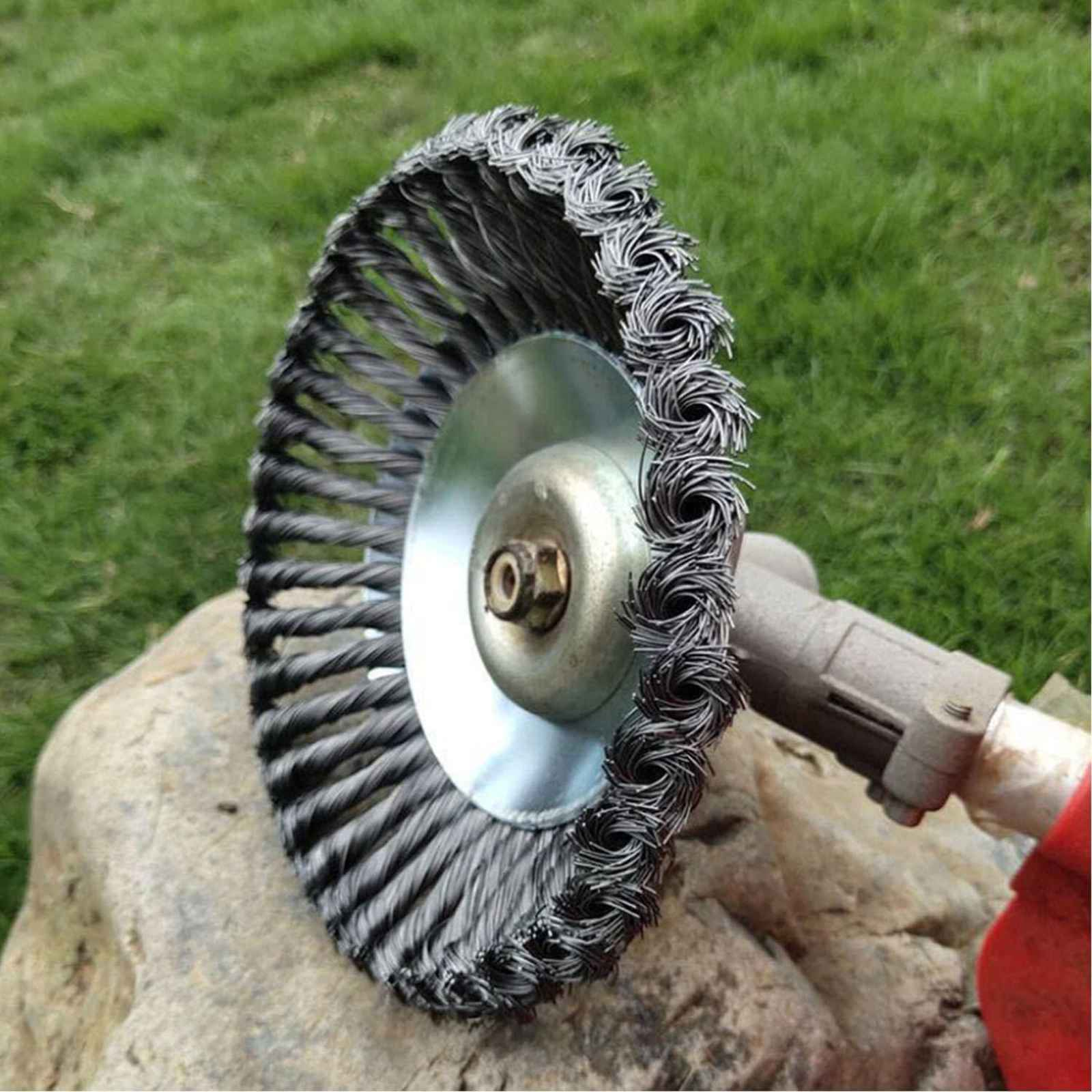 Nahaufnahme einer Metalldrahtbürste für eine Motorsense, auf einem Felsen platziert, grünes Gras im Hintergrund.