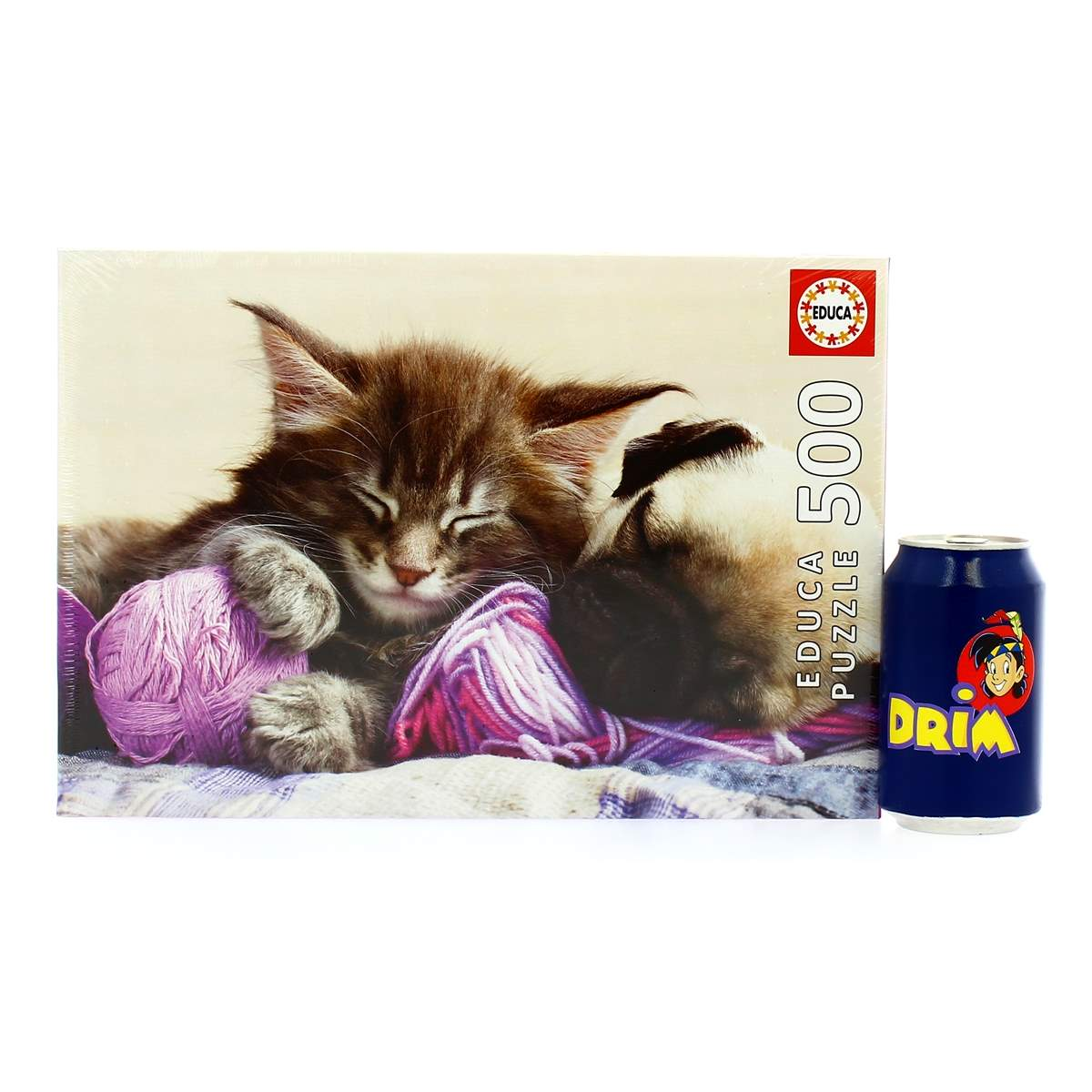Una caja de rompecabezas con un gatito durmiendo, una madeja de lana y una lata de DRIM.