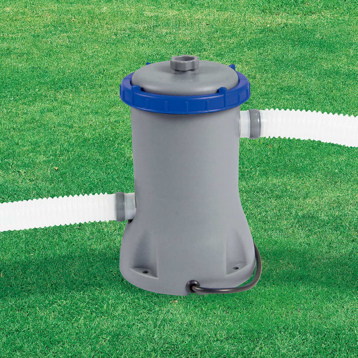 Een grijze zwembadfilterpomp met blauwe accenten en slangen, op een grasveld.