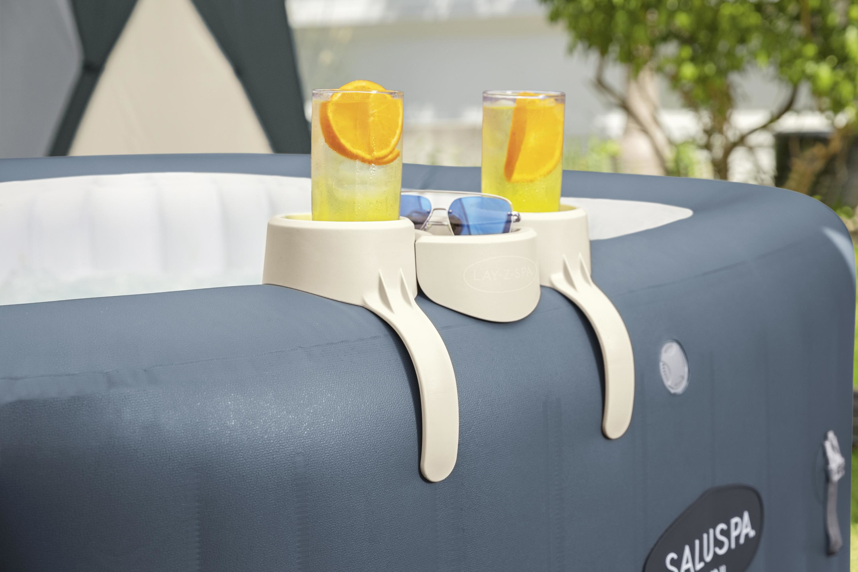 Twee drankjes met sinaasappelschijfjes en zonnebril op de rand van een jacuzzi. Achtergrond groen.