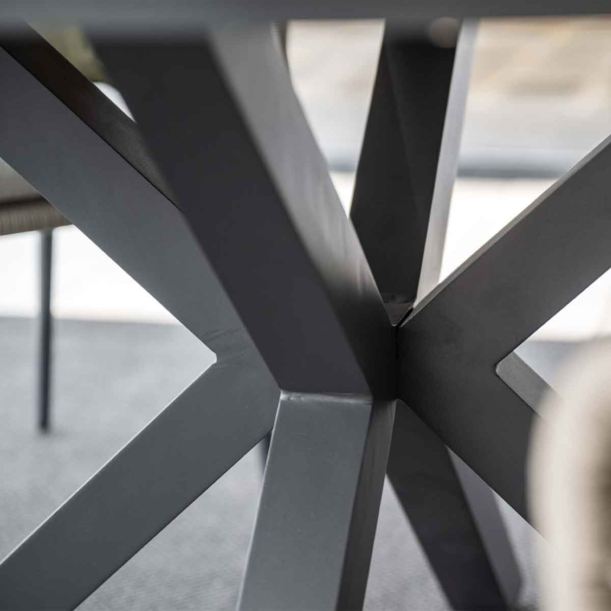 Close-up of a metal table leg with an X-shaped design.