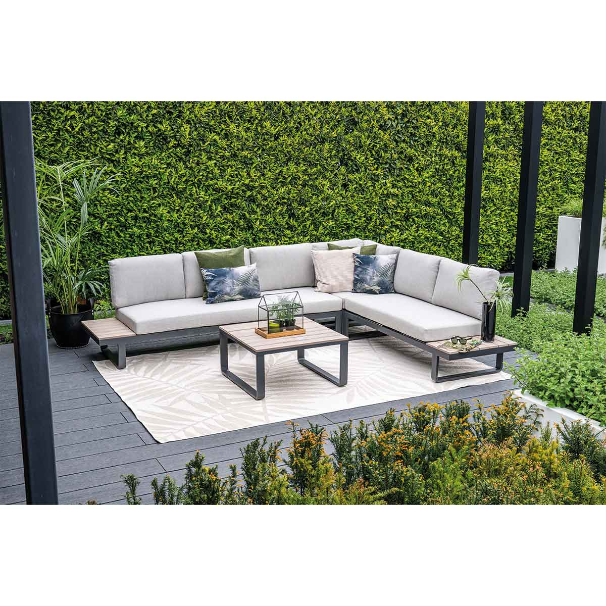 An outdoor sectional couch with light gray cushions and a black metal frame, accessorized with various pillows and a table.
