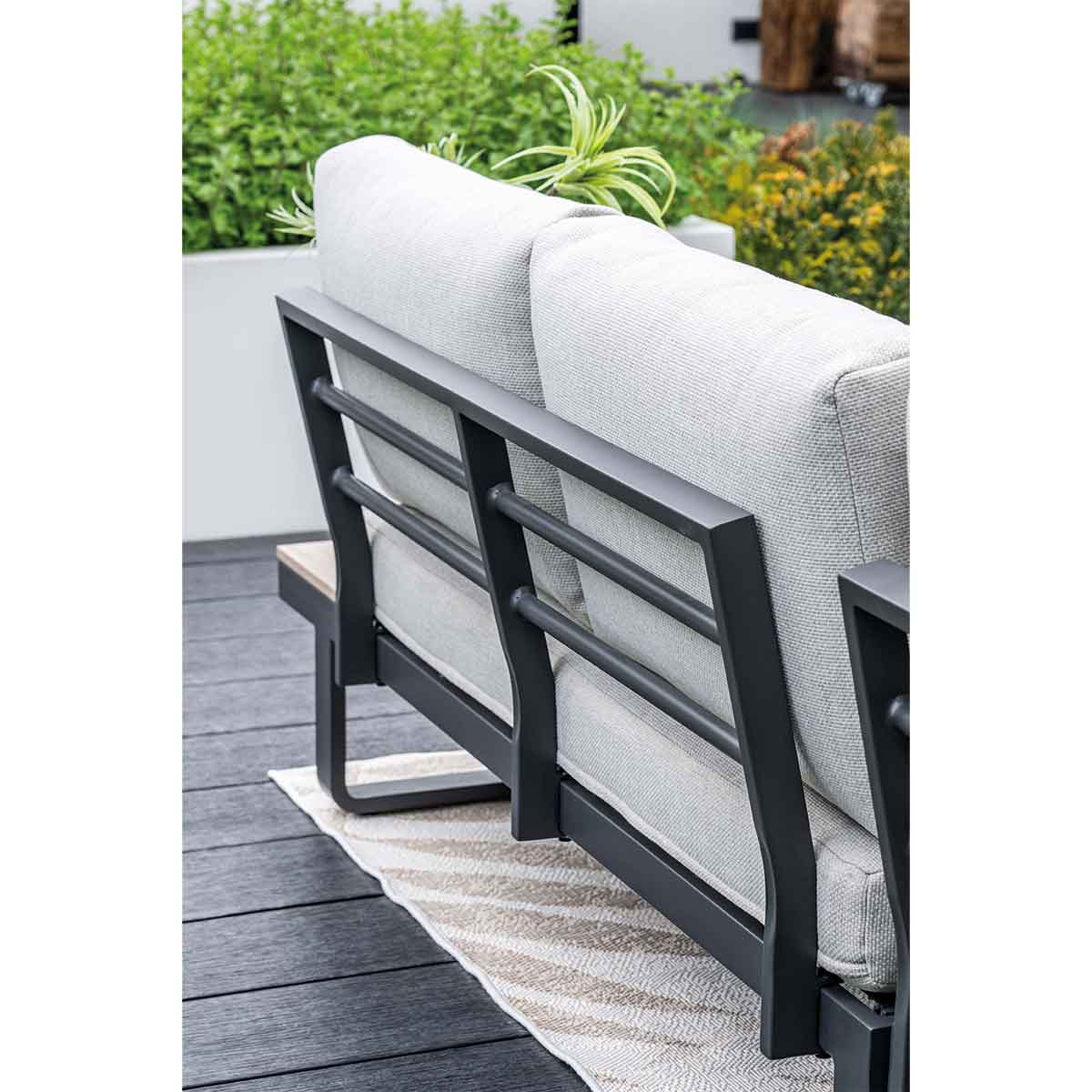 A close-up shows the back of an outdoor sectional couch with light gray cushions and a black metal frame.