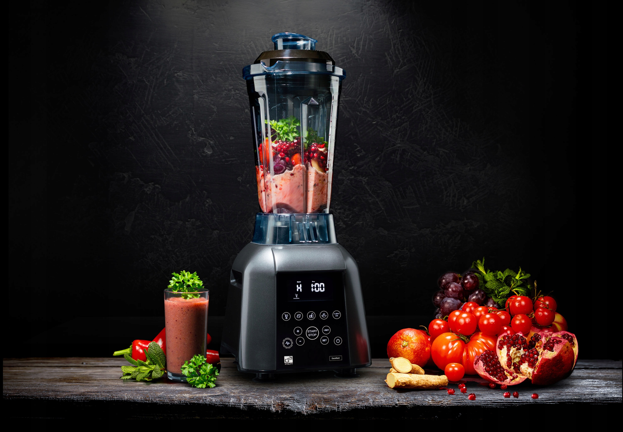 Blender wypełniony owocami i warzywami, z szklanką smoothie po lewej stronie i owocami po prawej.