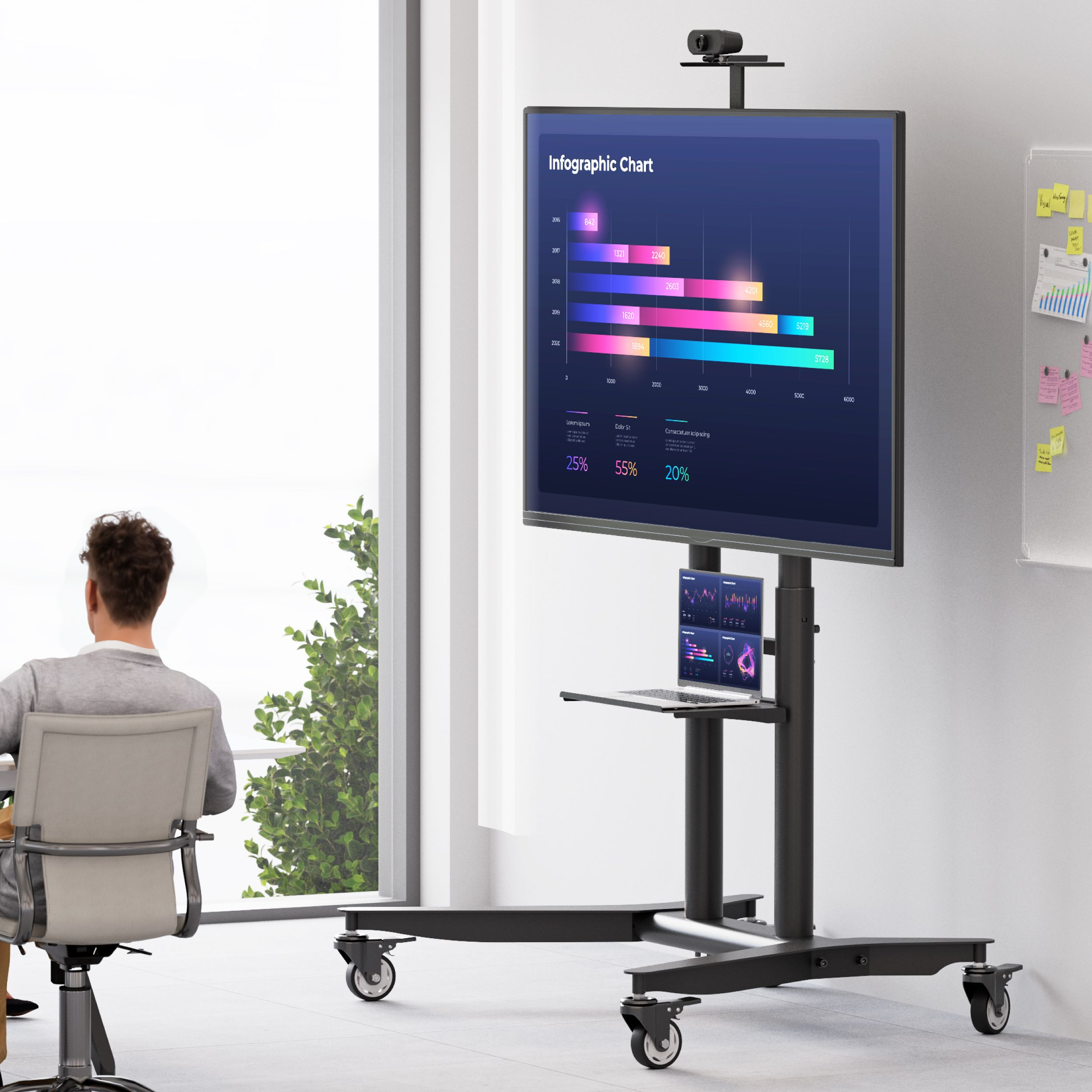 Mężczyzna siedzi przed telewizorem na stojaku. Ekran wyświetla wykres infograficzny. Poniżej laptop.