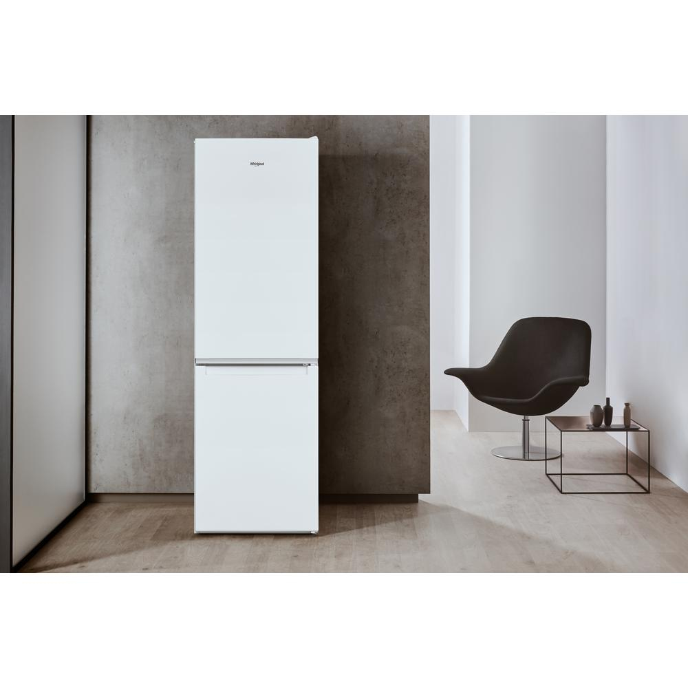 Un frigorifero Whirlpool bianco in un interno moderno con sedia nera e tavolino.