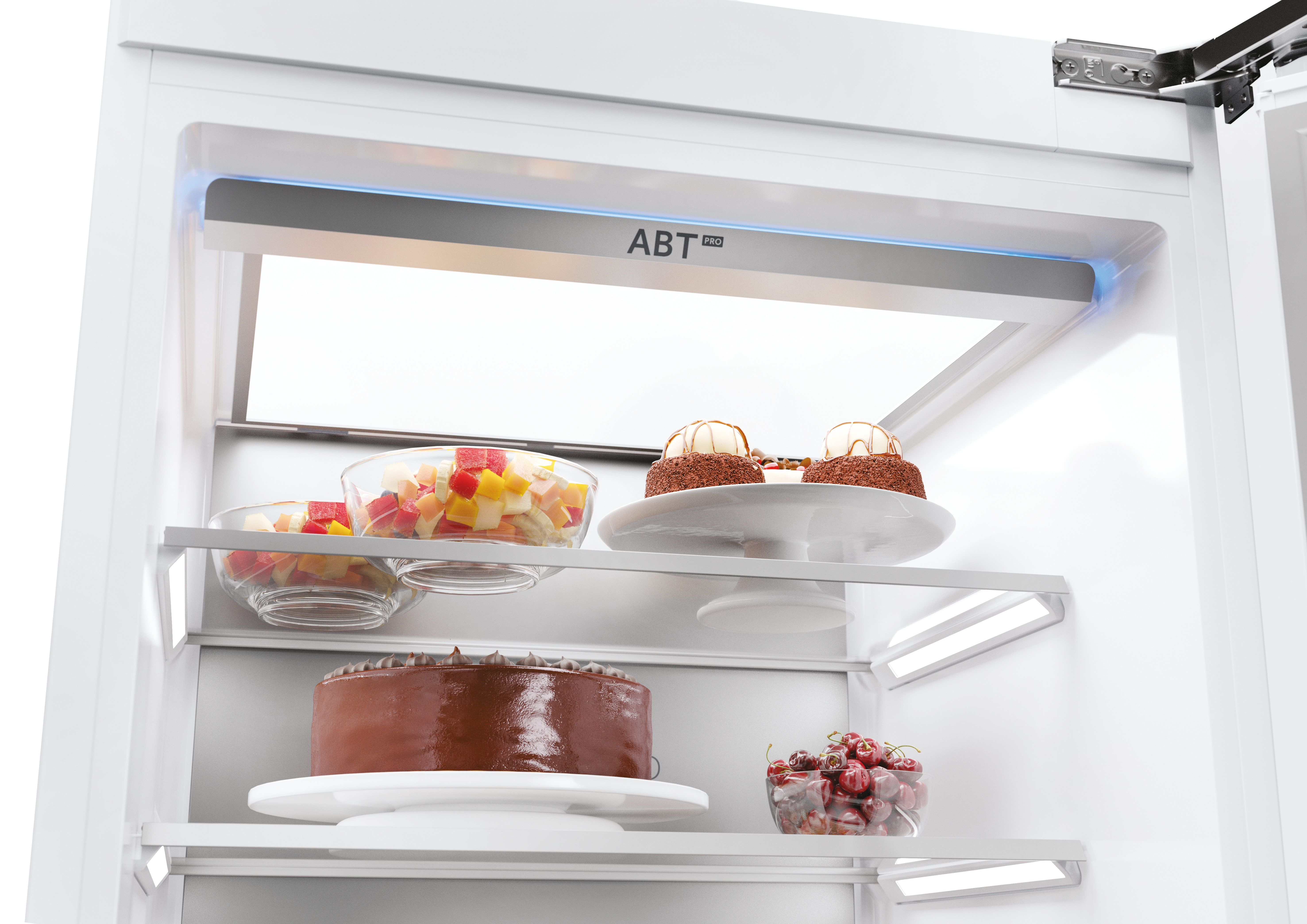 Primer plano del interior de un refrigerador. Muestra estantes con postres y un cuenco de fruta.
