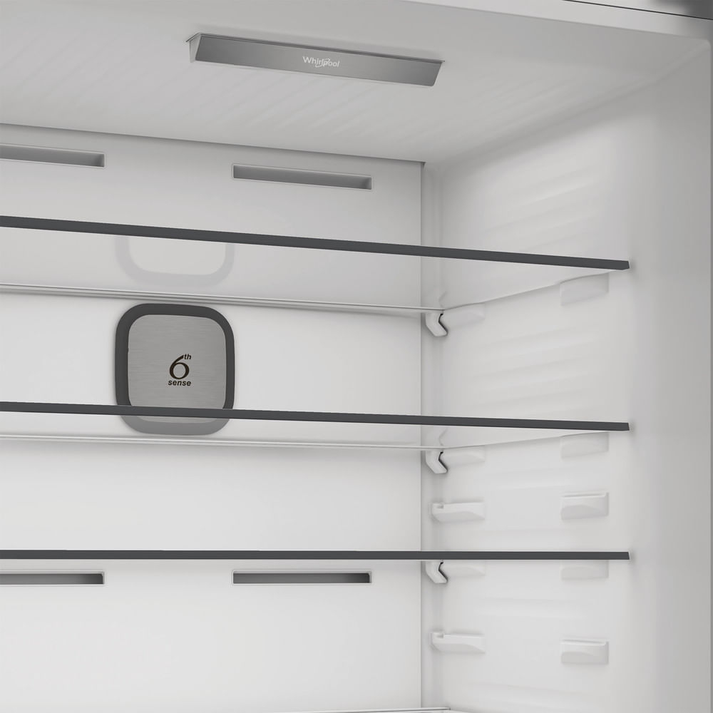 Interno del frigorifero bianco vuoto con ripiani e marchio Whirlpool.