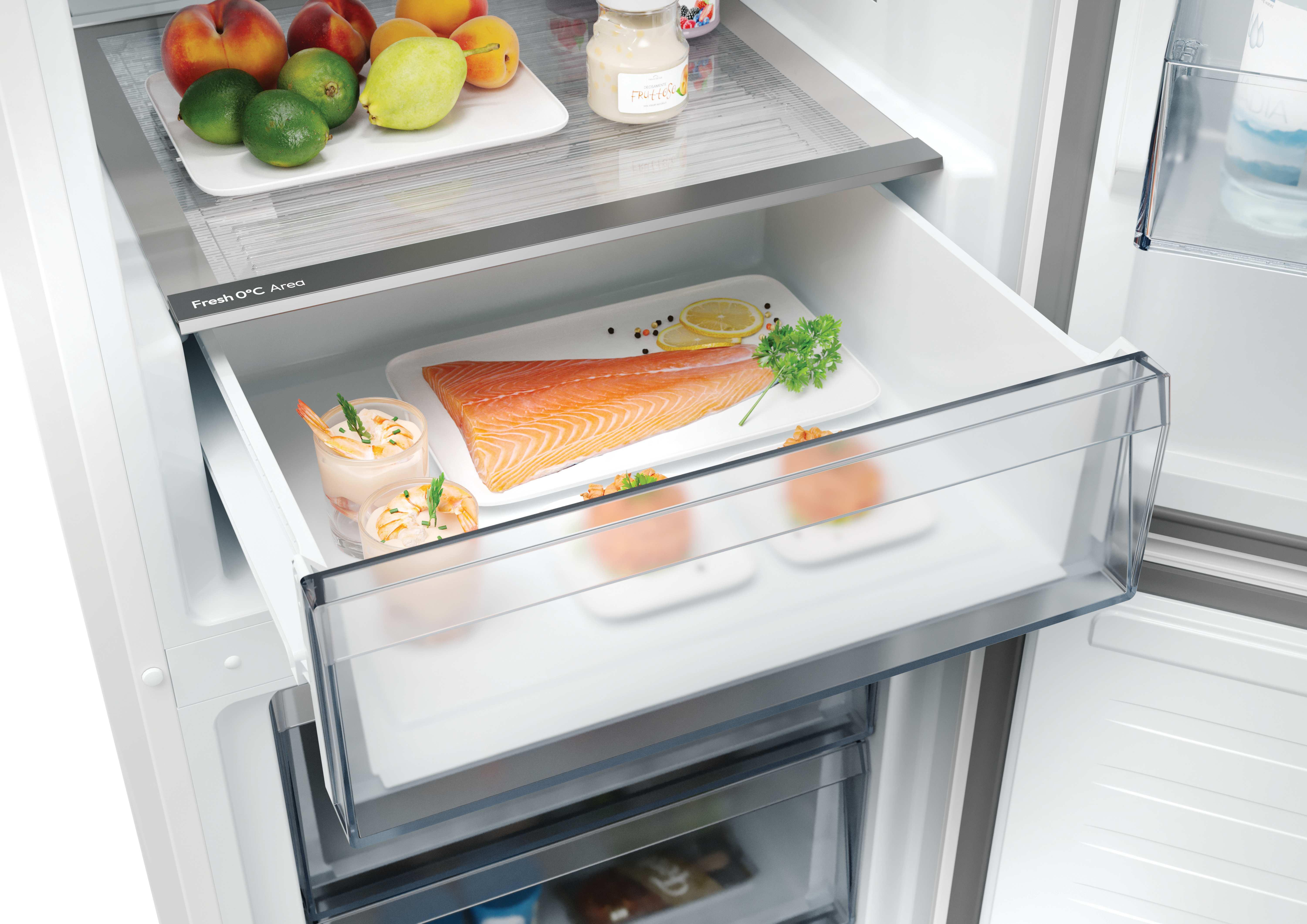 Un cajón del refrigerador contiene salmón, camarones y verduras. Otros estantes contienen productos. El refrigerador está abierto.